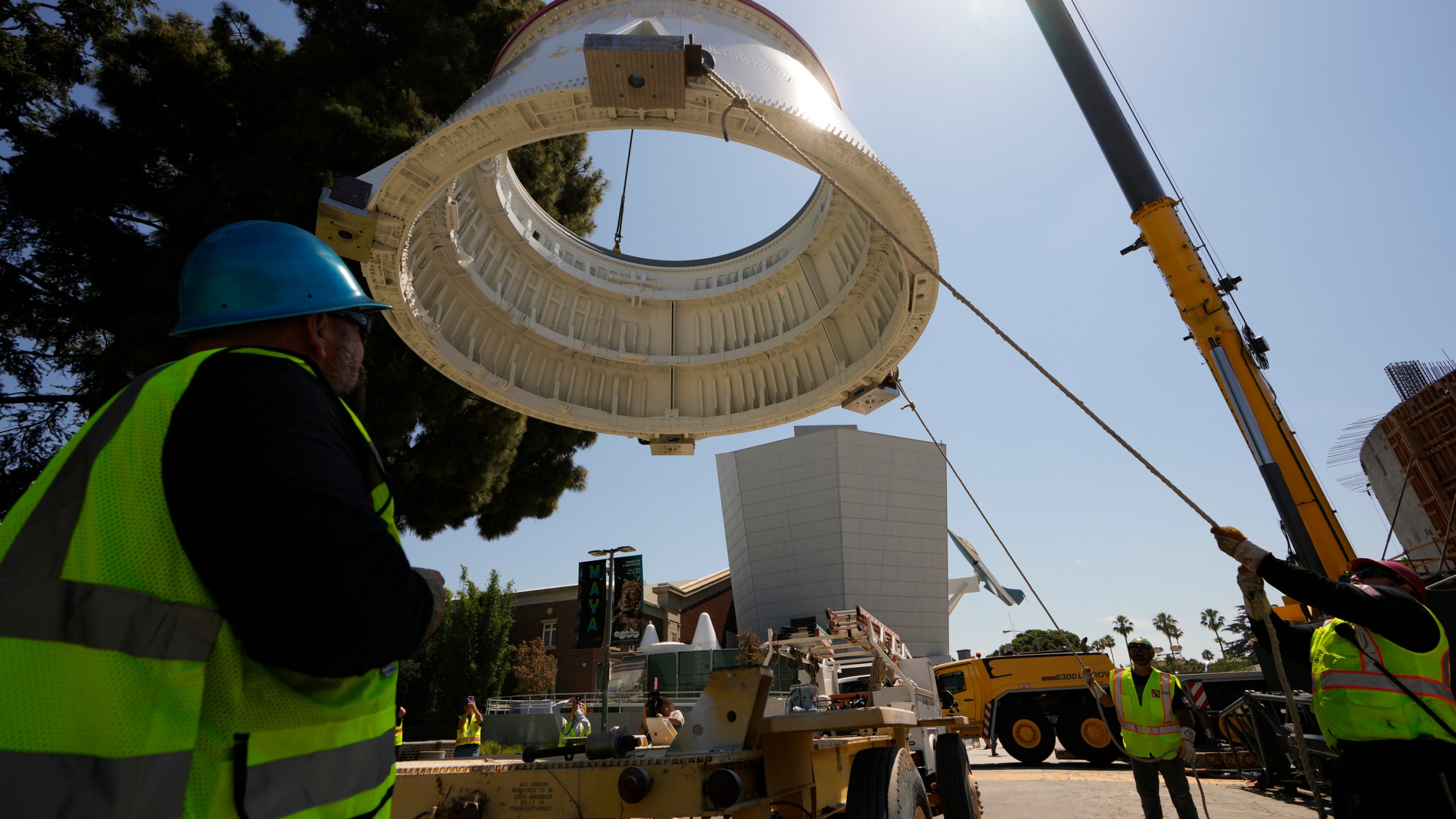 Workers used a crane to hoist the Solid Rocket Aft Skirts, the bottom segments of the boosters of the Space Shuttle Endeavour, before placing them on top of a seismic isolator pad inside the Shuttle Gallery at the Samuel Oschin Air and Space Center in Los Angeles, Thursday, July 20, 2023. (AP Photo/Damian Dovarganes)