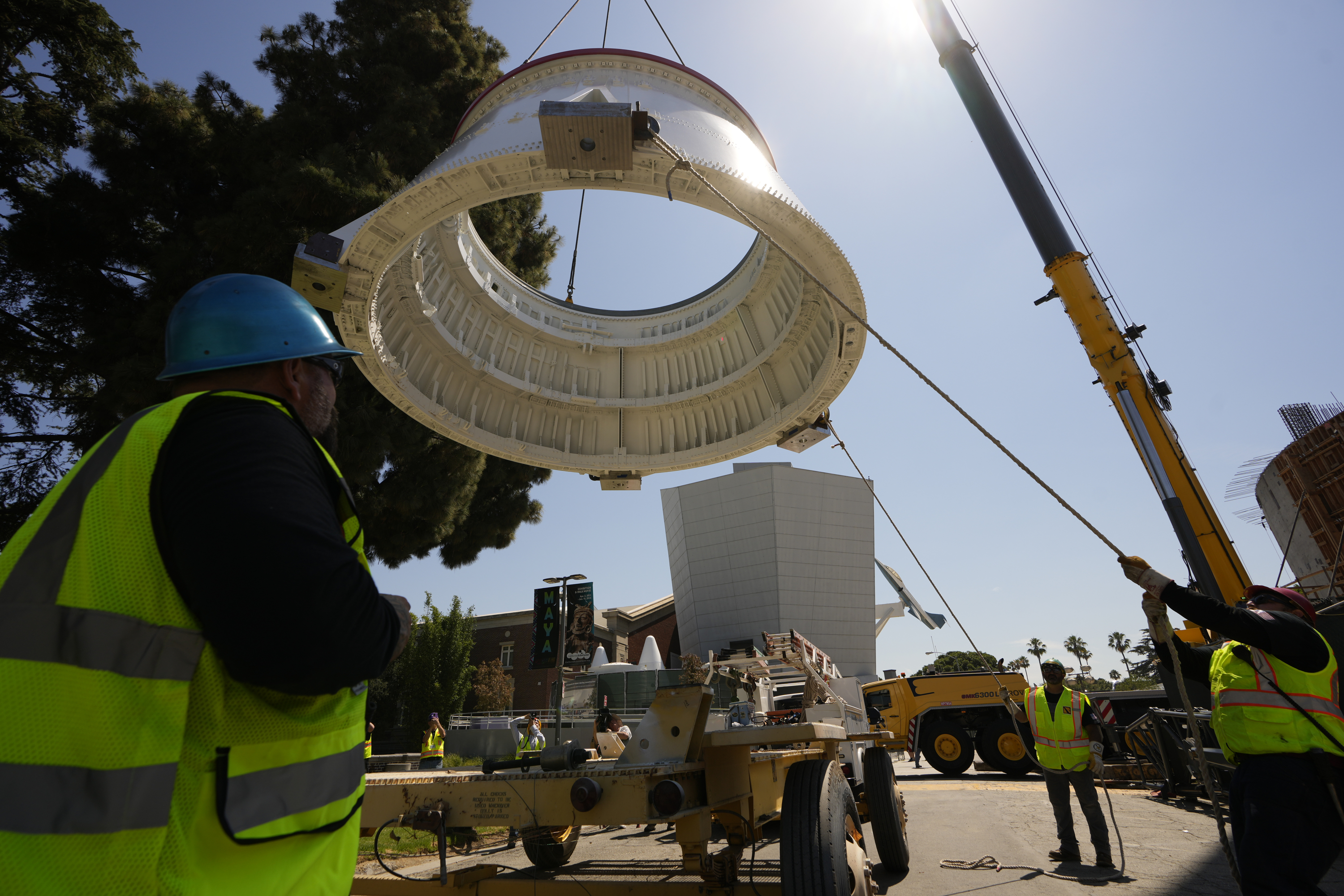 Workers used a crane to hoist the Solid Rocket Aft Skirts, the bottom segments of the boosters of the Space Shuttle Endeavour, before placing them on top of a seismic isolator pad inside the Shuttle Gallery at the Samuel Oschin Air and Space Center in Los Angeles, Thursday, July 20, 2023. (AP Photo/Damian Dovarganes)