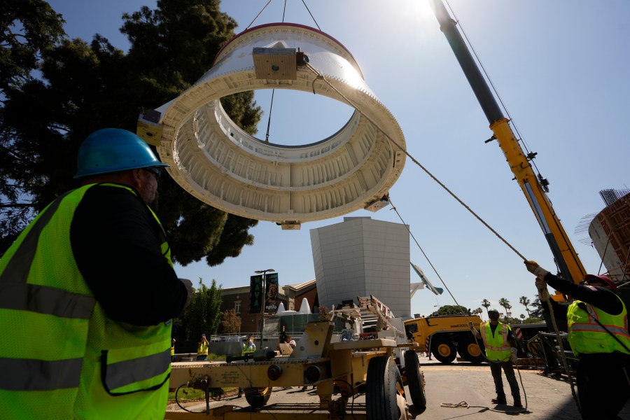 Workers used a crane to hoist the Solid Rocket Aft Skirts, the bottom segments of the boosters of the Space Shuttle Endeavour, before placing them on top of a seismic isolator pad inside the Shuttle Gallery at the Samuel Oschin Air and Space Center in Los Angeles, Thursday, July 20, 2023. (AP Photo/Damian Dovarganes)