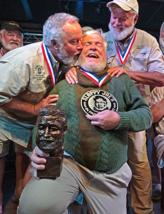 In this Saturday, July 22, 2023, photo provided by the Florida Keys News Bureau, Zach Taylor, left, and Jon Auvil, right, congratulate Gerrit Marshall, center, for winning the annual Hemingway Look-Alike Contest at Sloppy Joe's Bar in Key West, Fla. After 11 years of competing Marshall, a Madison, Wisc., resident, finally achieved success on his 68th birthday. The competition was a highlight of the annual Hemingway Days festival that ends Sunday, July 23. Ernest Hemingway lived in Key West throughout most of the 1930s. Taylor won in 2021, while Auvil was the 2022 winner. (Andy Newman/Florida Keys News Bureau via AP)