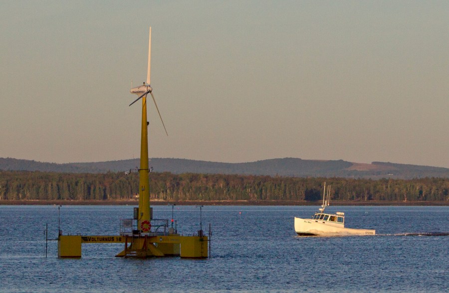 FILE - A lobster boat passes the country's first floating wind turbine off the coast of Castine, Maine, Sept. 20, 2013. Maine is poised to launch an offshore wind program to meet clean energy goals with a goal of producing enough power for about 900,000 homes from floating wind turbines in the Gulf of Maine. (AP Photo/Robert F. Bukaty)