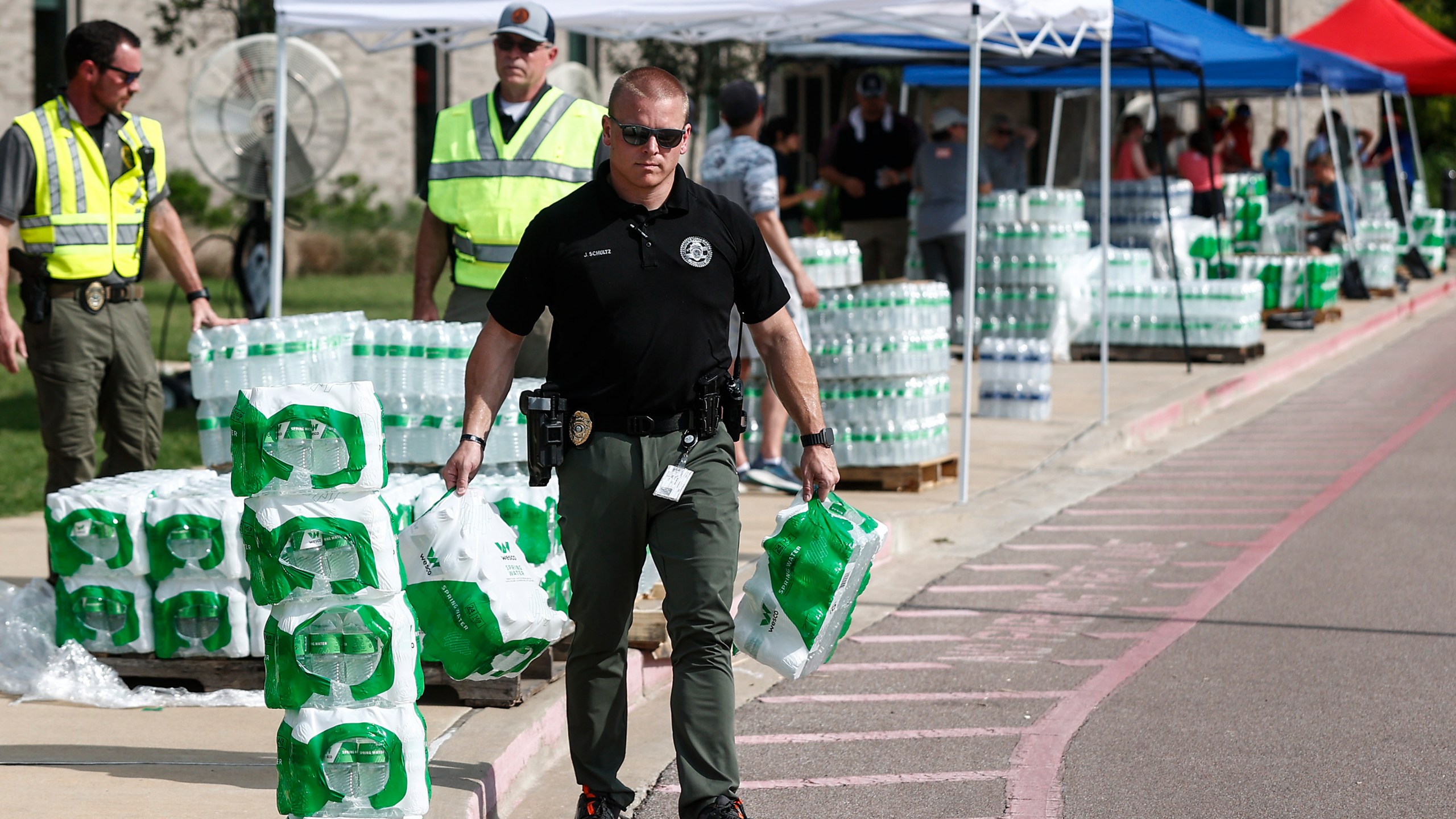 A police officer helps hand out bottled water to residents on Monday, July 24, 2023 at Forest Hill Elementary School in Germantown, Tenn. Residents of the Tennessee city were told that diesel fuel spilled into a local reservoir, and to avoid drinking tap water. People remain under an order Wednesday, July 26 to avoid using water for everything except flushing toilets. They can’t drink or boil tap water, or use it showering or bathing. (Mark Weber/Daily Memphian via AP)