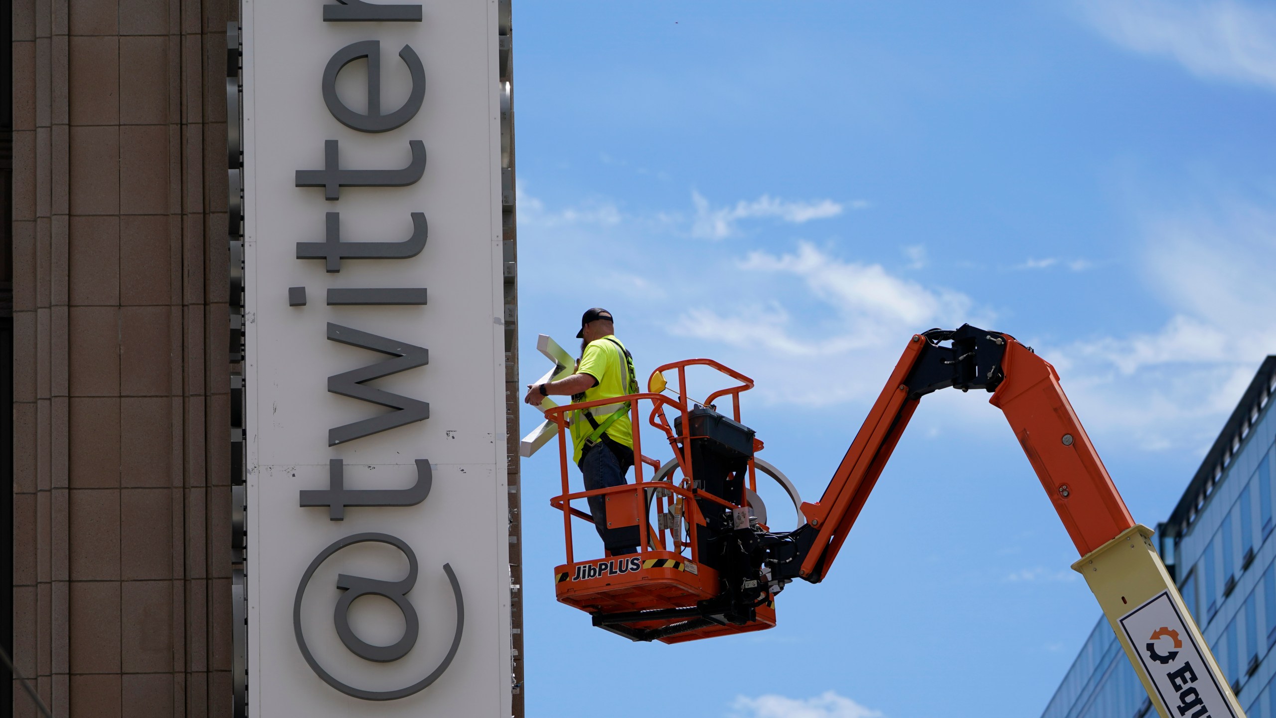 FILE - A workman removes a character from a sign on the Twitter headquarters building in San Francisco, Monday, July 24, 2023. Elon Musk may want to send “tweet” back to the birds, but the ubiquitous term for posting on the site he now calls X is here to stay, at least for now. For one, the word is still plastered all over the website formerly known as Twitter. Write a post, you still need to press a blue button that says “tweet” to publish it. To repost it, you still tap “retweet.” (AP Photo/Godofredo A. Vásquez, File)