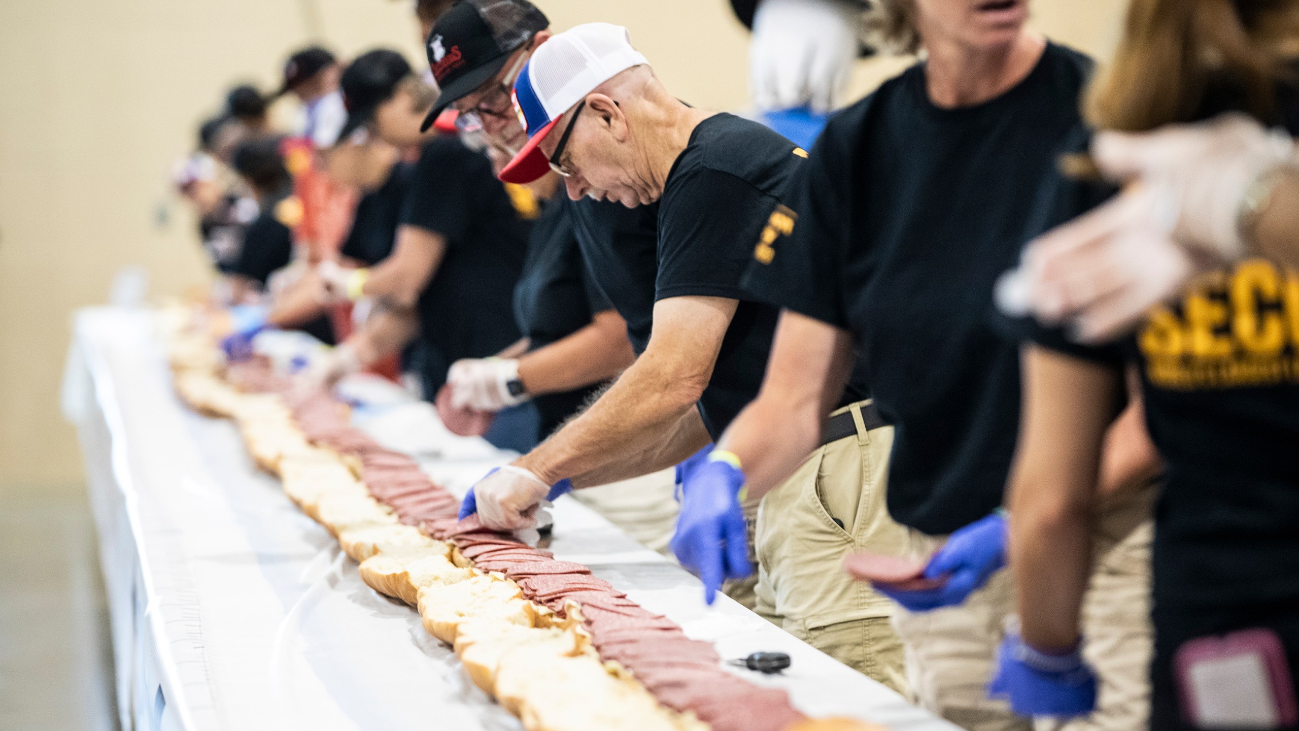 Volunteers assemble a 150-foot-long (45.7-meters-long) bologna sandwich at the Lebanon Area Fair on Tuesday, July 25, 2023 in Lebanon, Pa. Every footlong “bite” was sponsored at $100 per foot. The money was donated to Lebanon County Christian Ministries and their efforts to help people dealing with food insecurity in the Lebanon Valley. (Sean Simmers/The Patriot-News via AP)