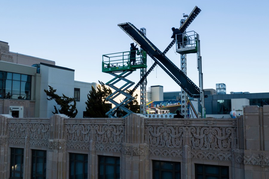 Workers install lighting on an “X” sign atop the company headquarters, formerly known as Twitter, in downtown San Francisco, on Friday, July 28, 2023. The city has launched an investigation into the sign as city officials say replacing letters or symbols on buildings, or erecting a sign on top of one, requires a permit. (AP Photo/Noah Berger)