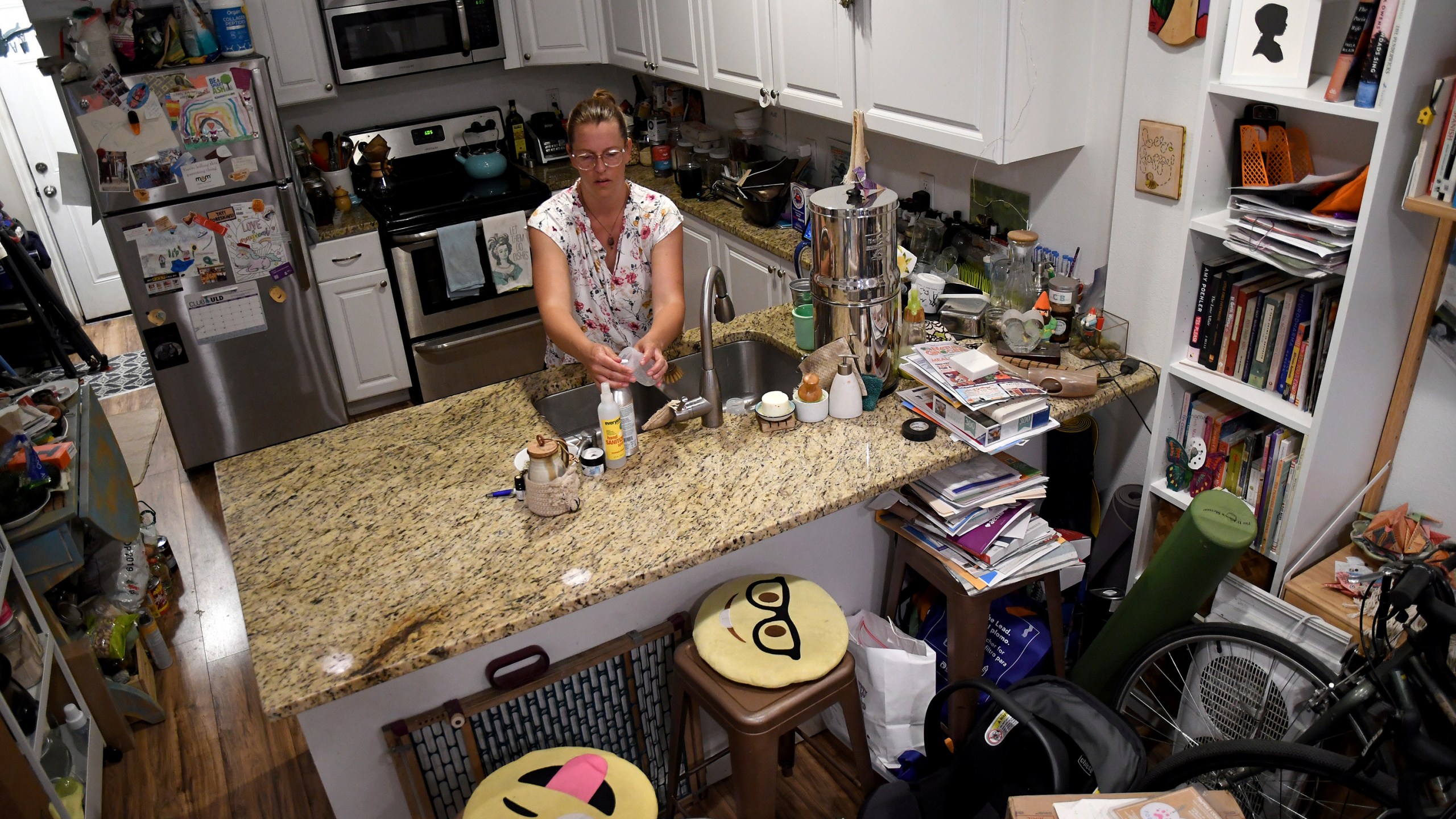 Amanda Morian washes dishes in her home in Denver's Globeville neighborhood on Monday, July 24, 2023. Morian, who has a 13-week-old baby susceptible to hot weather, is desperate to keep the house cool. She bought thermal curtains, ceiling fans and runs a window unit. At night, it's too hot to swaddle her newborn, but she tries to do skin-to-skin touch to regulate the baby's body temperature. Morian said that even with subsidies, she can't afford to install air conditioning. (AP Photo/Thomas Peipert)