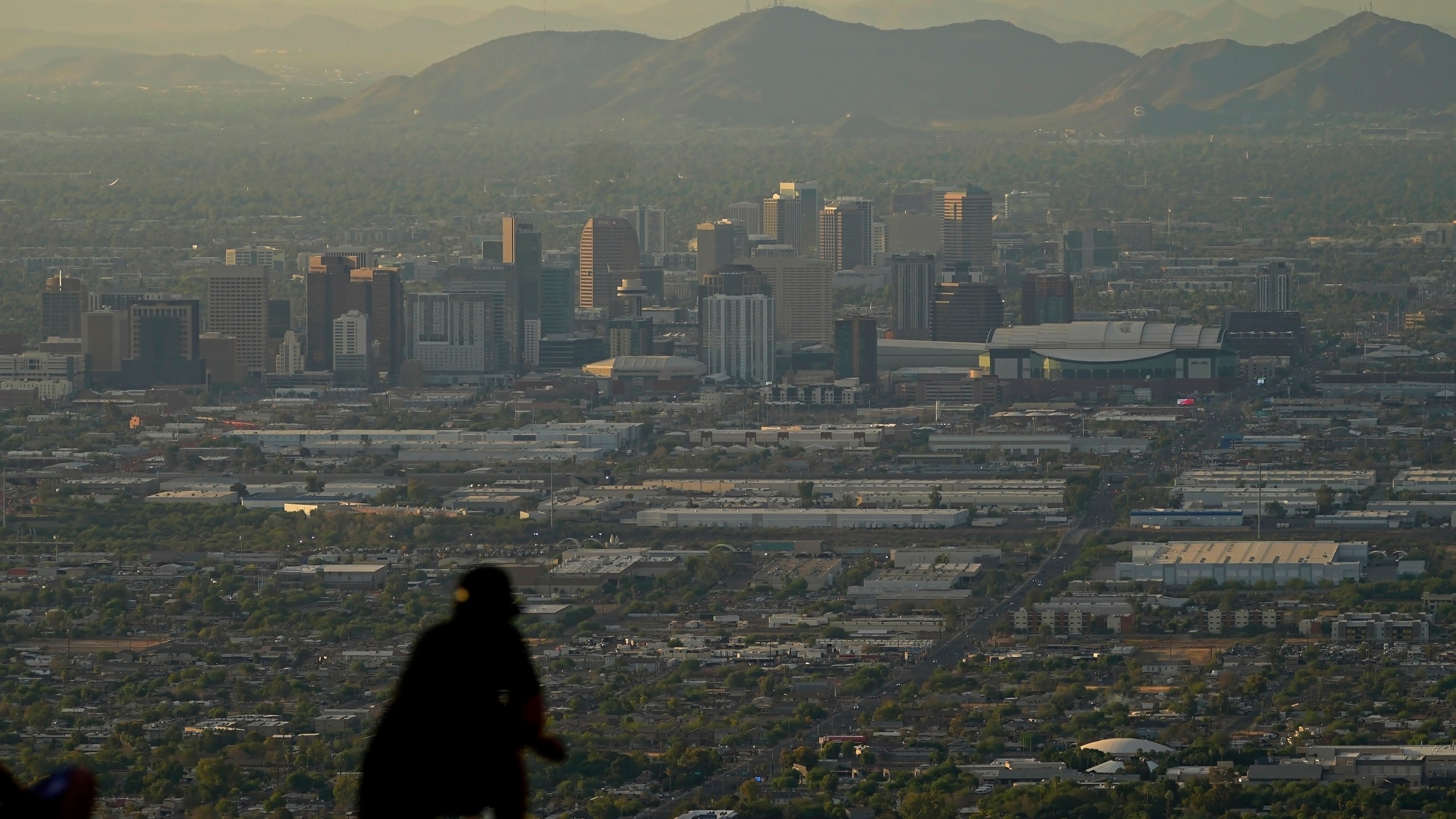 A man overlooks downtown Phoenix at sunset atop South Mountain, Sunday, July 30, 2023. Phoenix hit its 31st consecutive day of at least 110 degrees Fahrenheit (43.3 Celsius). The National Weather Service says the temperature climbed to a high of 111 degrees Fahrenheit before the day was through. Some slight relief may be on the way as seasonal thunderstorms could drop temperatures in Phoenix on Monday and Tuesday. (AP Photo/Matt York)