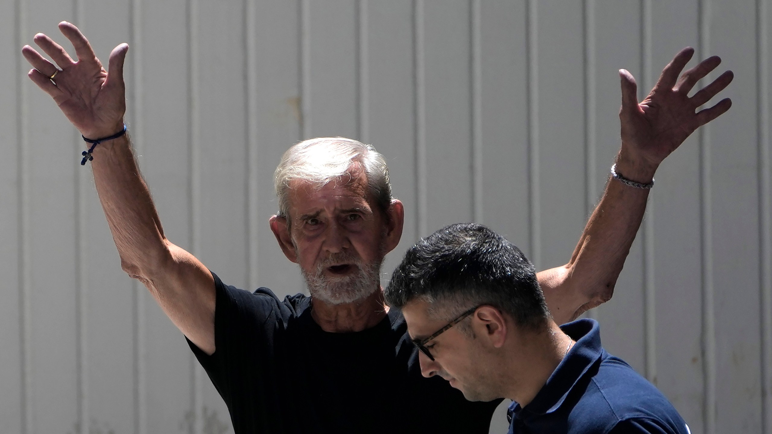 FILE - A police officer escorts British David Hunter from the grounds of the courthouse complex after a trial on a premeditated murder charge in the death of his wife, in Paphos, Cyprus, on July 21, 2023. A Cyprus court on Monday July 31, 2023 sentenced Hunter who killed his ailing wife in their retirement home to two years in prison, rejecting a defense request to hand down a suspended sentence after convicting him earlier of manslaughter. (AP Photo/Petros Karadjias, File)