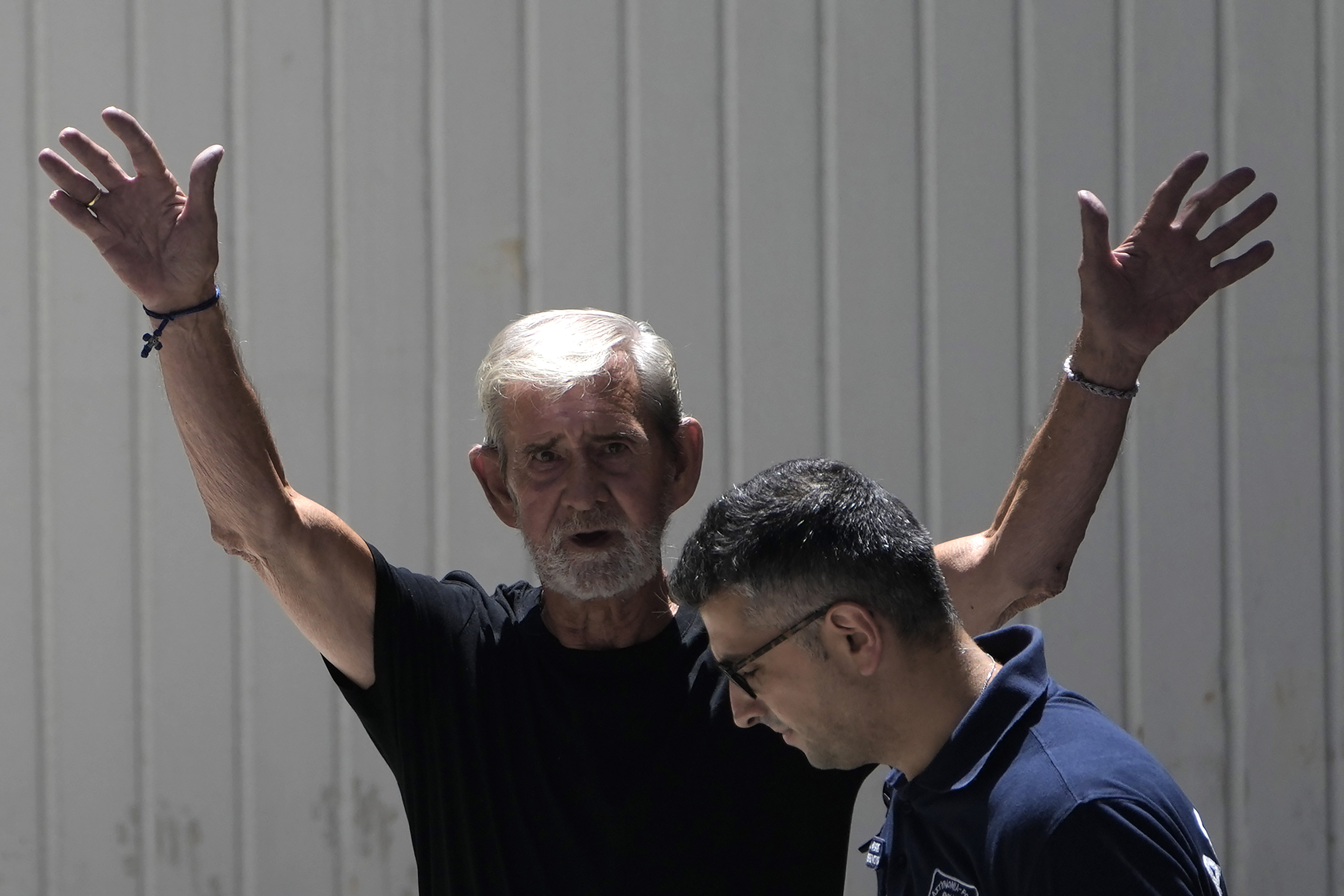 FILE - A police officer escorts British David Hunter from the grounds of the courthouse complex after a trial on a premeditated murder charge in the death of his wife, in Paphos, Cyprus, on July 21, 2023. A Cyprus court on Monday July 31, 2023 sentenced Hunter who killed his ailing wife in their retirement home to two years in prison, rejecting a defense request to hand down a suspended sentence after convicting him earlier of manslaughter. (AP Photo/Petros Karadjias, File)