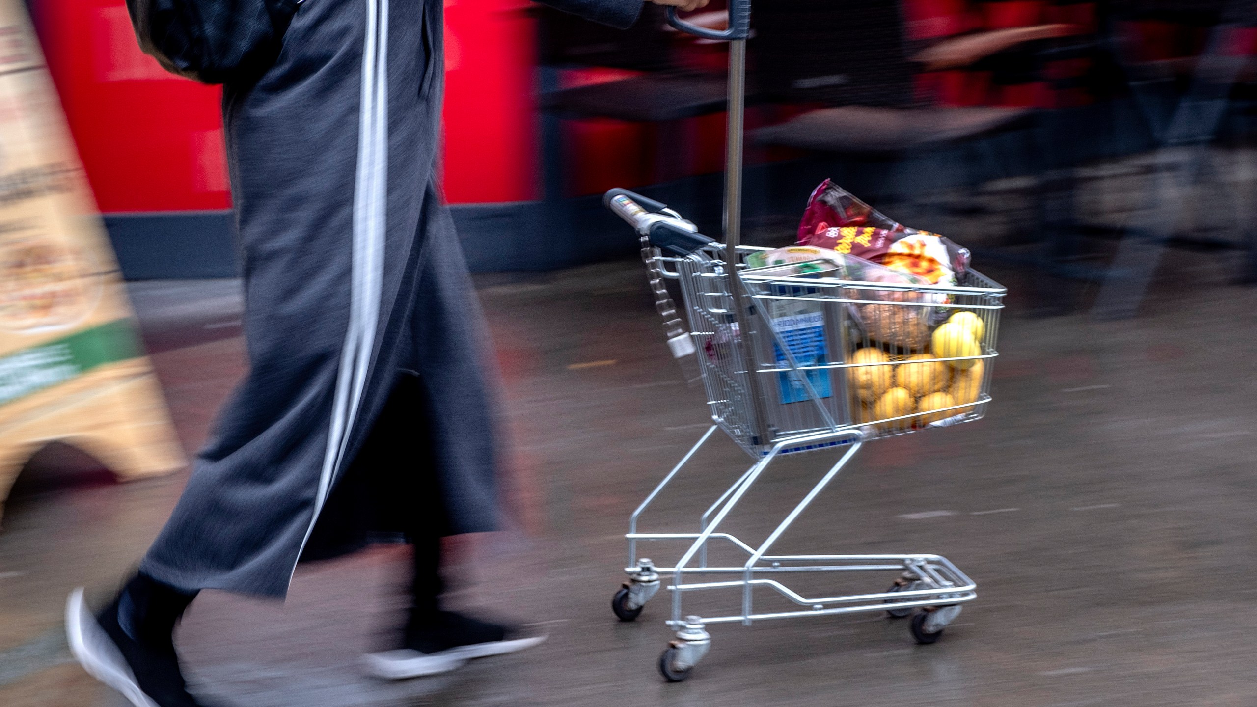 FILE - A woman pushes a small shopping cart outside a discount market in Frankfurt, Germany, on July 27, 2023. The European economy grew modestly in the most recent quarter, breaking out of a months of stagnation or contraction as higher interest rates designed to fight inflation make it more expensive for households and businesses to borrow, invest and spend. (AP Photo/Michael Probst, File)