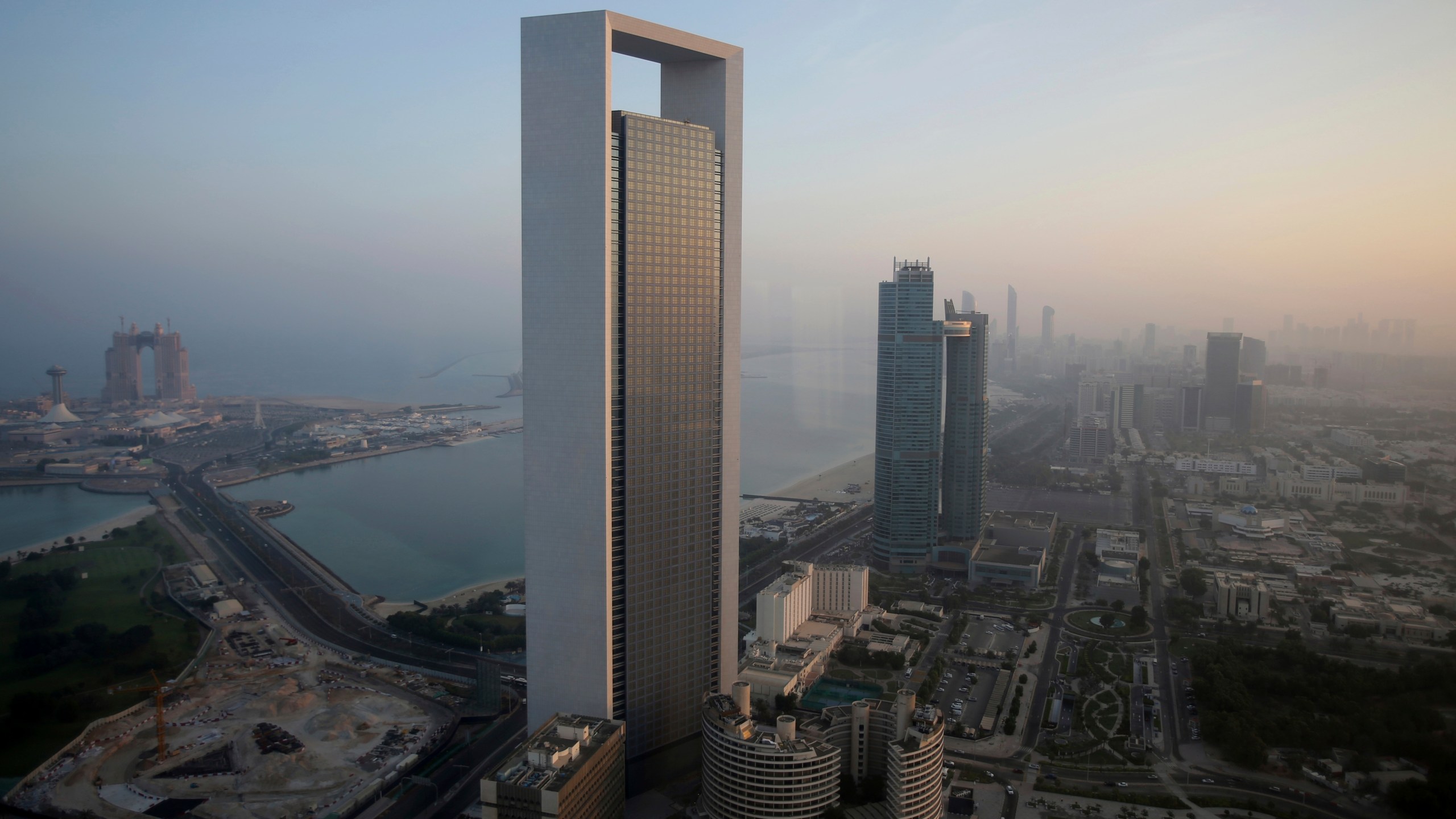 FILE - The sun rises over the headquarters of the Abu Dhabi National Oil Co. headquarters that dominates the skyline in Abu Dhabi, United Arab Emirates, on Nov. 7, 2016. The state-run oil giant in the United Arab Emirates, ADNOC, said Monday July 31, 2023 it has moved up its target for achieving net zero emissions in its operations to 2045, as the country prepares to host U.N. climate talks later this year. (AP Photo/Kamran Jebreili, File)