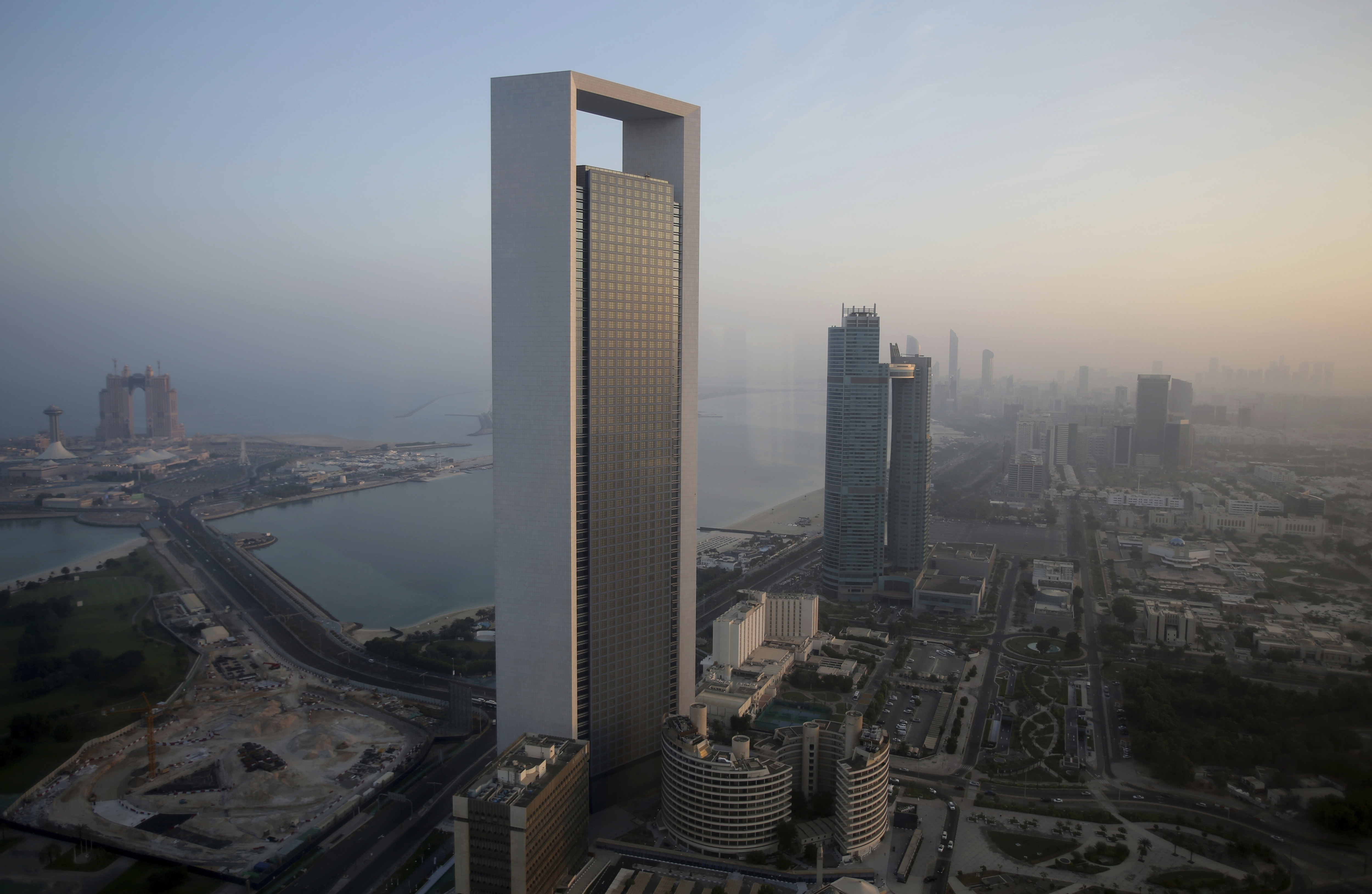 FILE - The sun rises over the headquarters of the Abu Dhabi National Oil Co. headquarters that dominates the skyline in Abu Dhabi, United Arab Emirates, on Nov. 7, 2016. The state-run oil giant in the United Arab Emirates, ADNOC, said Monday July 31, 2023 it has moved up its target for achieving net zero emissions in its operations to 2045, as the country prepares to host U.N. climate talks later this year. (AP Photo/Kamran Jebreili, File)