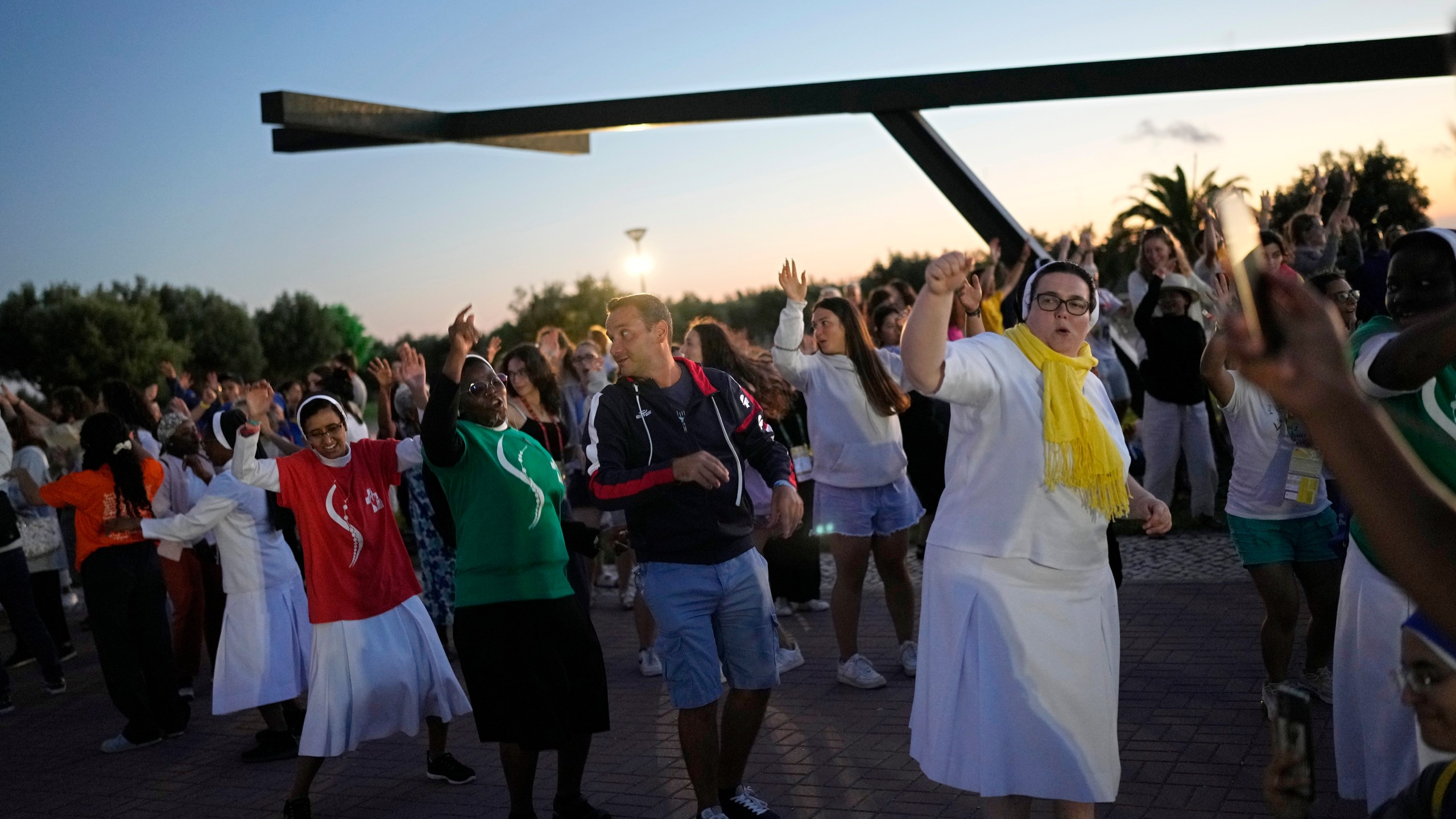 FILE- Faithful sing and dance to Christian songs before a vigil attended by people arriving early for the World Youth Day at a viewpoint overlooking Lisbon from across the Tagus River, in Almada, Portugal, as night falls, Friday, July 28, 2023. When Pope Francis made the first foreign trip of his papacy, to Rio de Janeiro for World Youth Day in 2013, he urged young people to make a "mess" in their local churches, to shake things up even if it ruffled the feathers of their bishops. (AP Photo/Andre Penner, File)