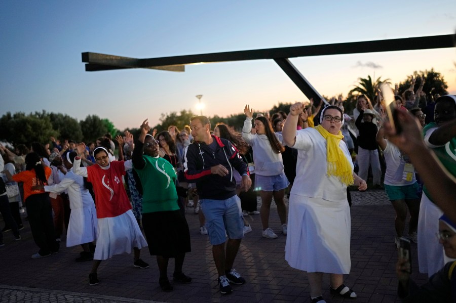 FILE- Faithful sing and dance to Christian songs before a vigil attended by people arriving early for the World Youth Day at a viewpoint overlooking Lisbon from across the Tagus River, in Almada, Portugal, as night falls, Friday, July 28, 2023. When Pope Francis made the first foreign trip of his papacy, to Rio de Janeiro for World Youth Day in 2013, he urged young people to make a "mess" in their local churches, to shake things up even if it ruffled the feathers of their bishops. (AP Photo/Andre Penner, File)