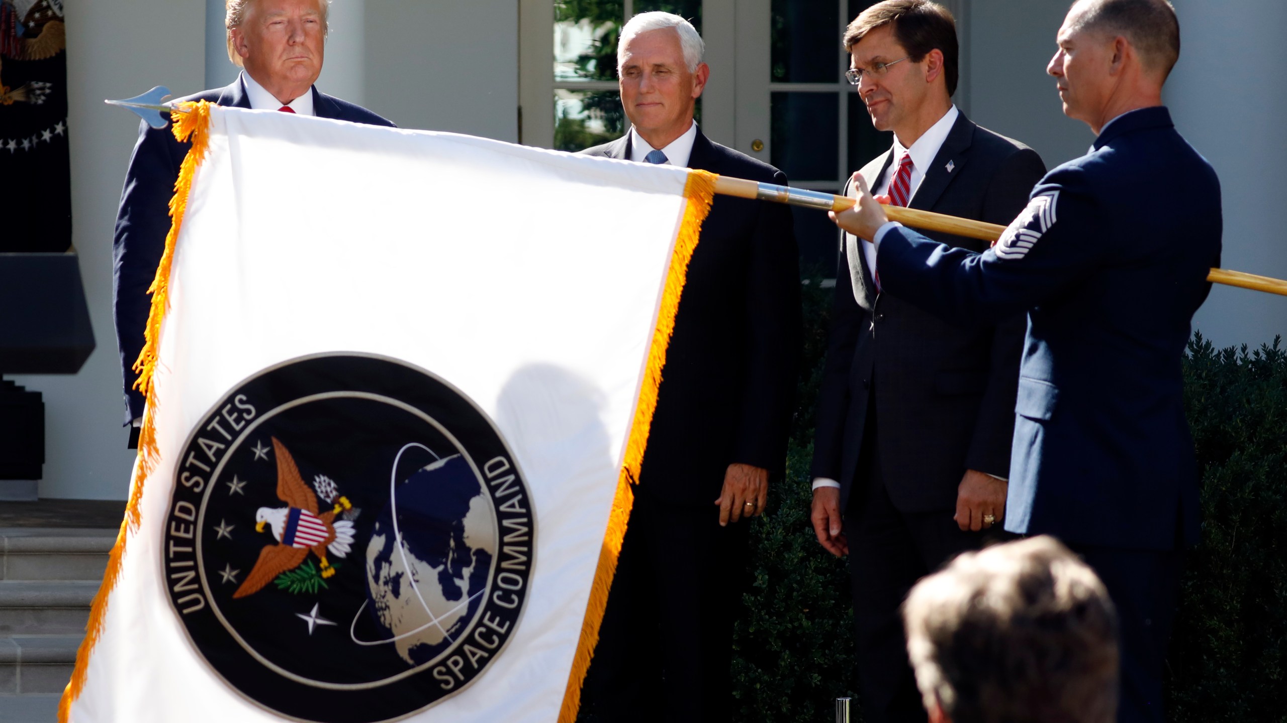 FILE - In this Aug. 29, 2019, file photo, President Donald Trump, left, watches with Vice President Mike Pence and Defense Secretary Mark Esper as the flag for U.S. space Command is unfurled as Trump announces the establishment of the U.S. Space Command in the Rose Garden of the White House in Washington. President Joe Biden has decided to keep U.S. Space Command headquarters in Colorado, overturning a last-ditch decision by the Trump administration to move it to Alabama and ending months of politically fueled debate, according to senior U.S. officials. (AP Photo/Carolyn Kaster, File)