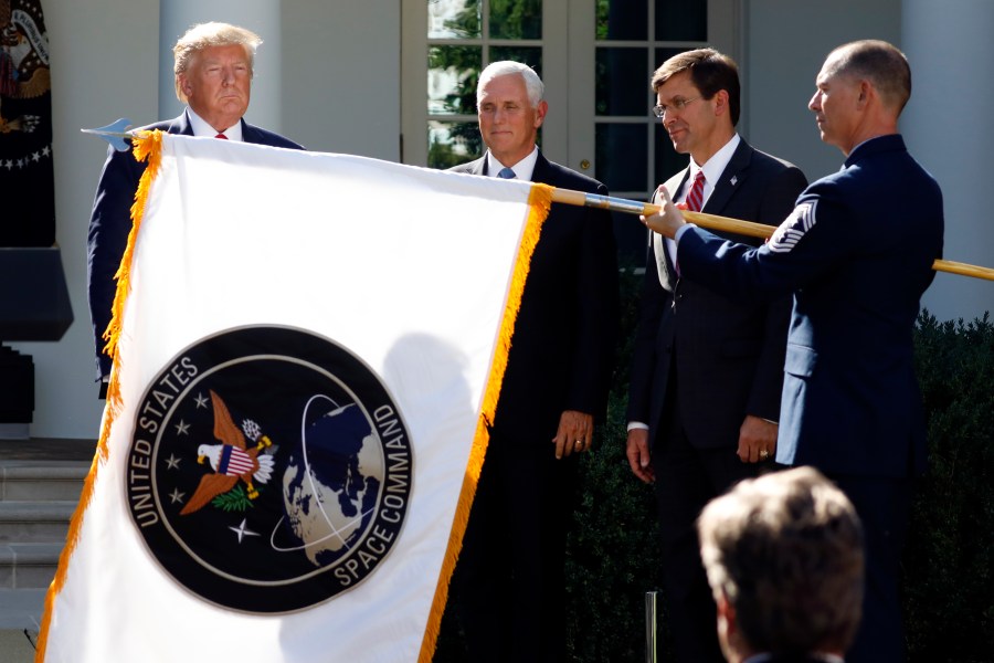 FILE - In this Aug. 29, 2019, file photo, President Donald Trump, left, watches with Vice President Mike Pence and Defense Secretary Mark Esper as the flag for U.S. space Command is unfurled as Trump announces the establishment of the U.S. Space Command in the Rose Garden of the White House in Washington. President Joe Biden has decided to keep U.S. Space Command headquarters in Colorado, overturning a last-ditch decision by the Trump administration to move it to Alabama and ending months of politically fueled debate, according to senior U.S. officials. (AP Photo/Carolyn Kaster, File)