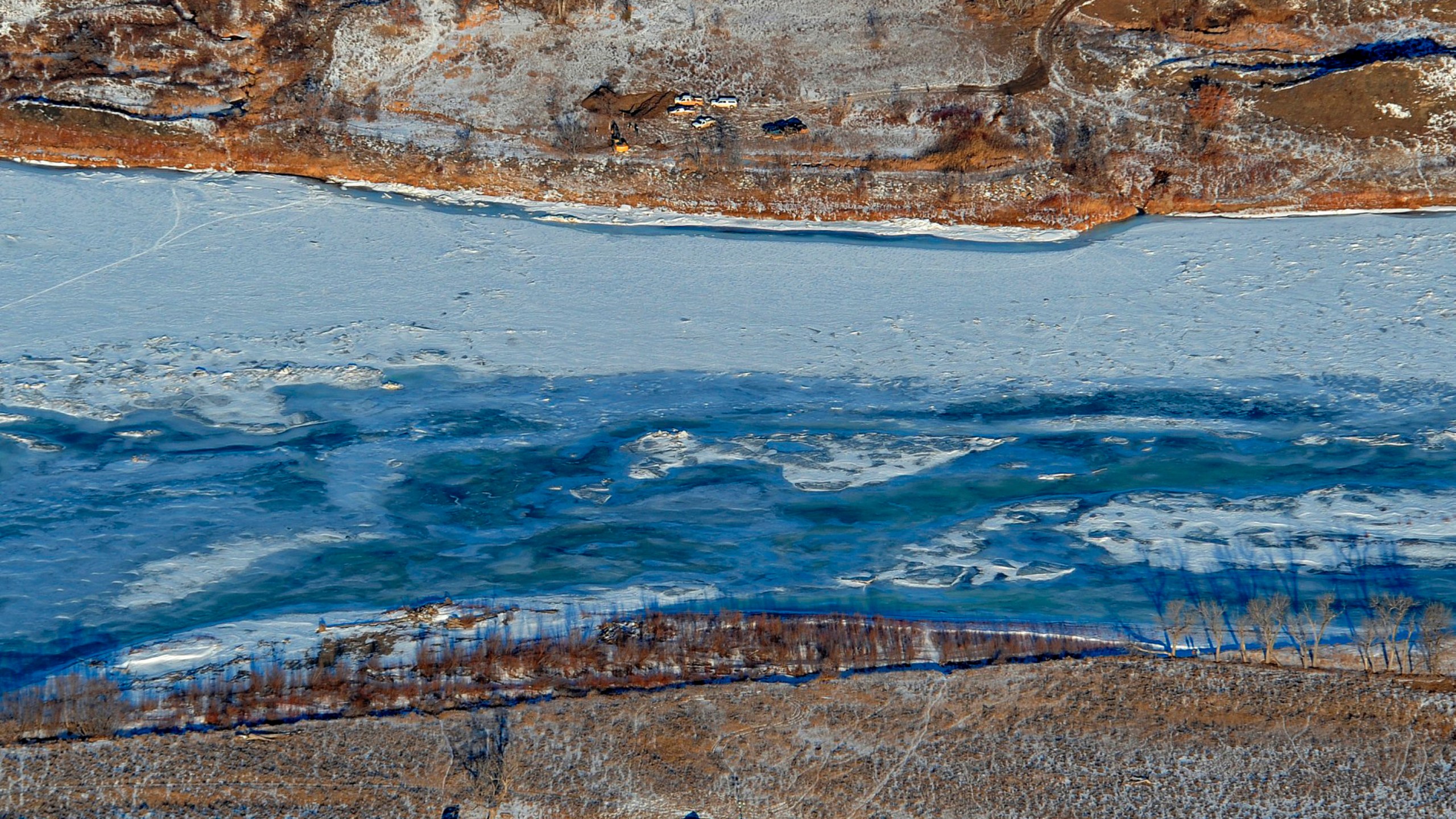 FILE - Photo crews work to contain an oil spill from Bridger Pipeline's broken pipeline near Glendive, Mont., on Jan. 19, 2015, in this aerial view showing both sides of the river. The U.S. Environmental Protection Agency on Monday, July 31, 2023, announced the settlement in a 2022 federal court lawsuit. Belle Fourche Pipeline Company and Bridger Pipeline LLC will pay the $12.5 million to resolve the claims made under the Clean Water Act and Pipeline Safety Laws, EPA said. (Larry Mayer/The Billings Gazette via AP, File)