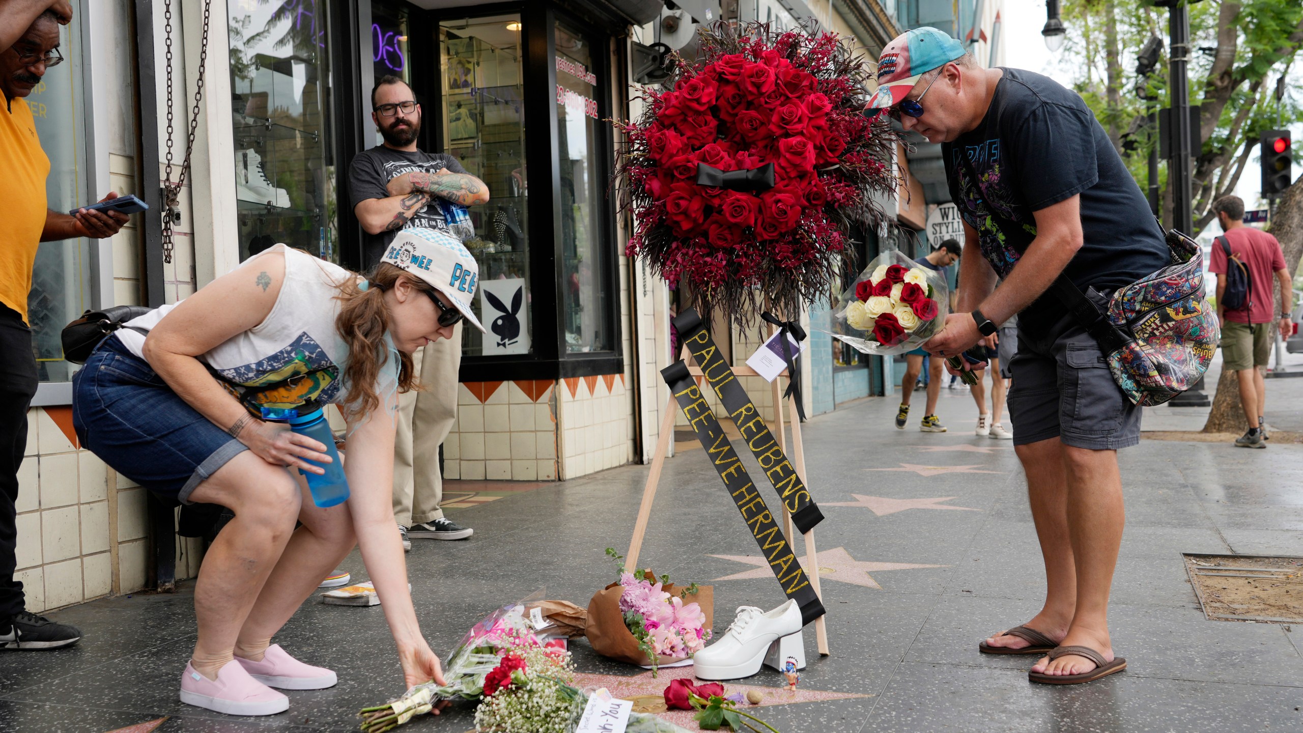 Sandy Neads, left, and James Owens lay flowers down on the star of Pee-wee Herman on the Hollywood Walk of Fame, Monday, July 31, 2023, in Los Angeles. Paul Reubens, the actor and comedian who created the Pee-wee Herman character, died Sunday night after a six-year struggle with cancer. (AP Photo/Chris Pizzello)