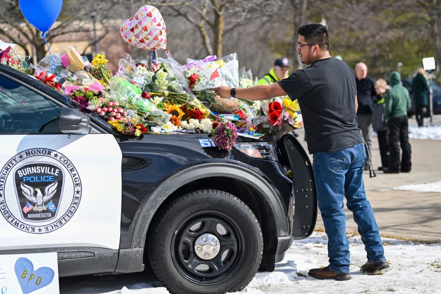 Crasto Cruz Reyes of Austin, Minn., places flowers at one of the three memorial vehicles in front of the Burnsville Police Department in Burnsville, Minn., Monday, Feb. 19, 2024. Two police officers and a firefighter who responded to a domestic situation at a suburban Minneapolis home were killed early Sunday during a standoff by a heavily armed man who shot at police from the home where seven children were also inside. (Craig Lassig/Pioneer Press via AP)