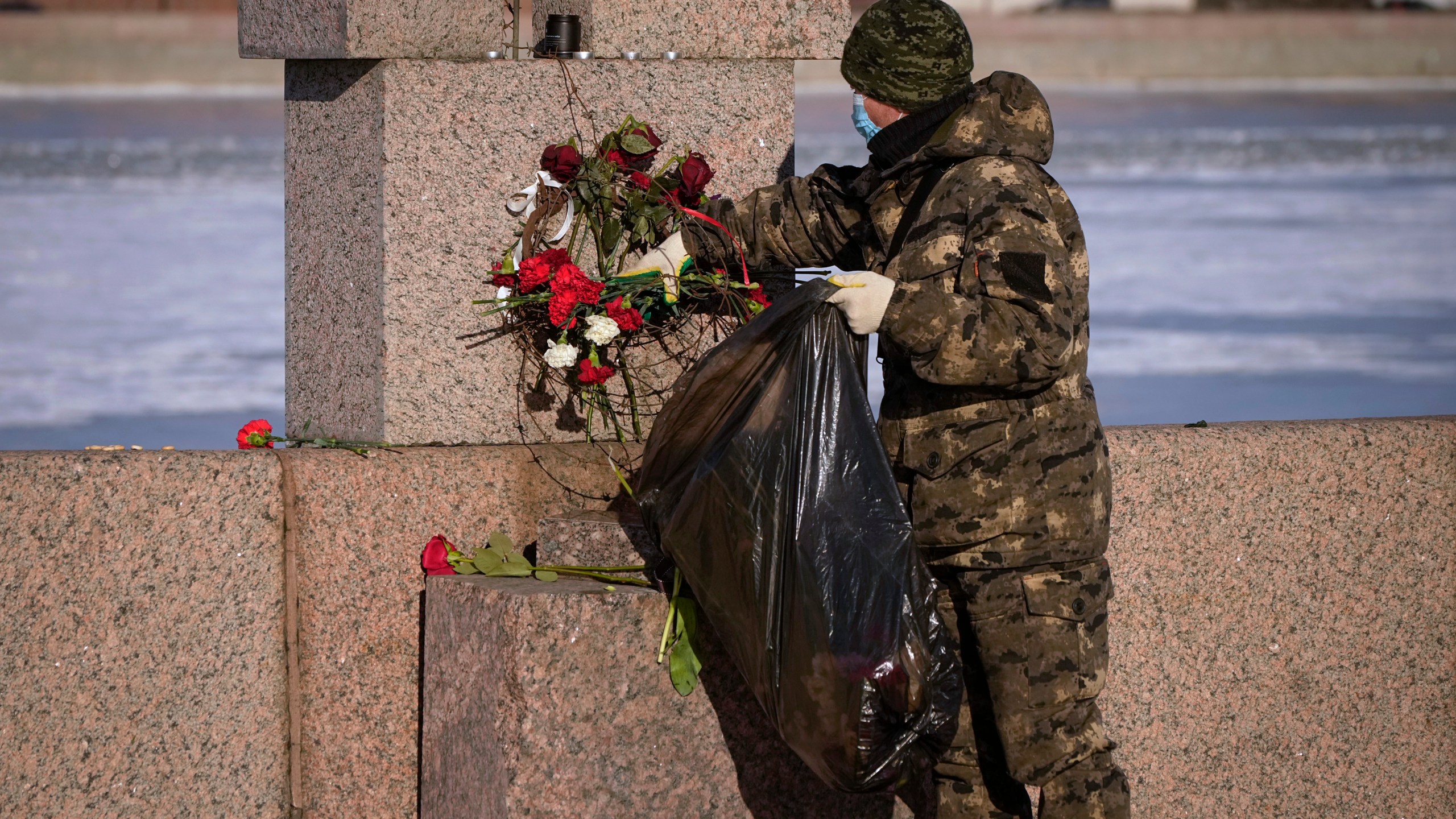 A municipal worker, on orders from the authorities, removes flowers brought by people to pay respect to Alexei Navalny from the Memorial to Victims of Political Repression in St. Petersburg, Russia, Monday, Feb. 19, 2024. Russians across the vast country streamed to ad-hoc memorials with flowers and candles to pay tribute to Alexei Navalny, the most famous Russian opposition leader and the Kremlin's fiercest critic. Russian officials reported that Navalny, 47, died in prison on Friday. (AP Photo/Dmitri Lovetsky)