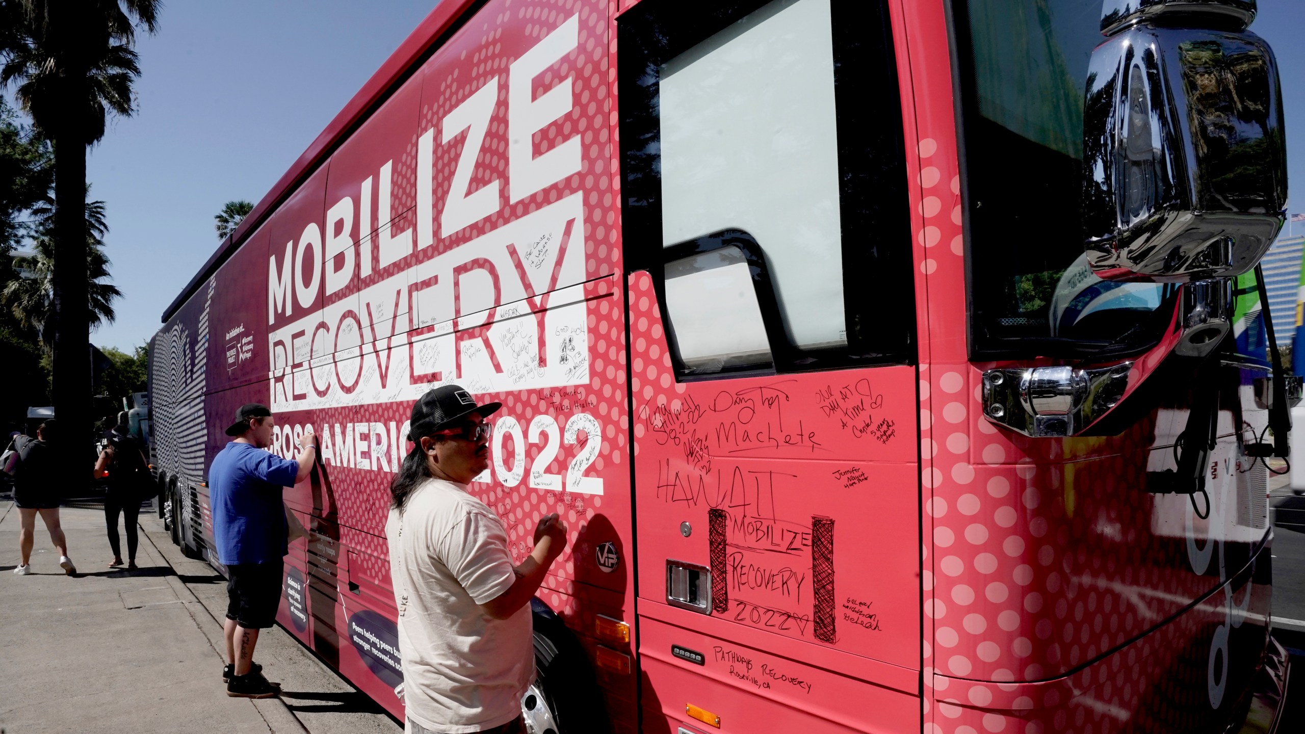 FILE - Sa Thao signs the 2022 Mobile Recovery National Bus, a nationwide bus tour drawing attention to determine how billions in opioid settlement money should be used, during a stop in Sacramento, Calif. Sept. 7, 2022. (AP Photo/Rich Pedroncelli, File)