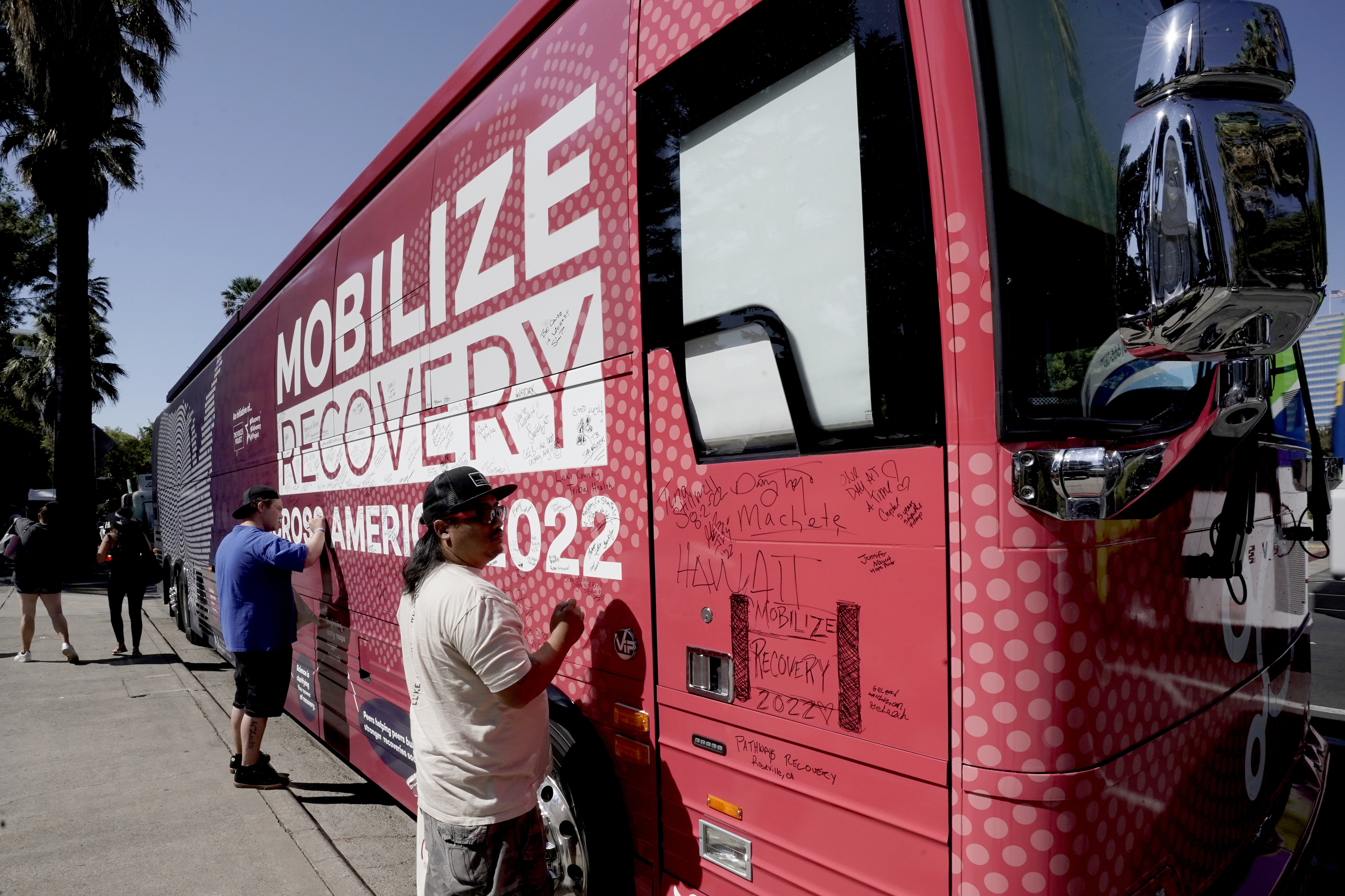 FILE - Sa Thao signs the 2022 Mobile Recovery National Bus, a nationwide bus tour drawing attention to determine how billions in opioid settlement money should be used, during a stop in Sacramento, Calif. Sept. 7, 2022. (AP Photo/Rich Pedroncelli, File)