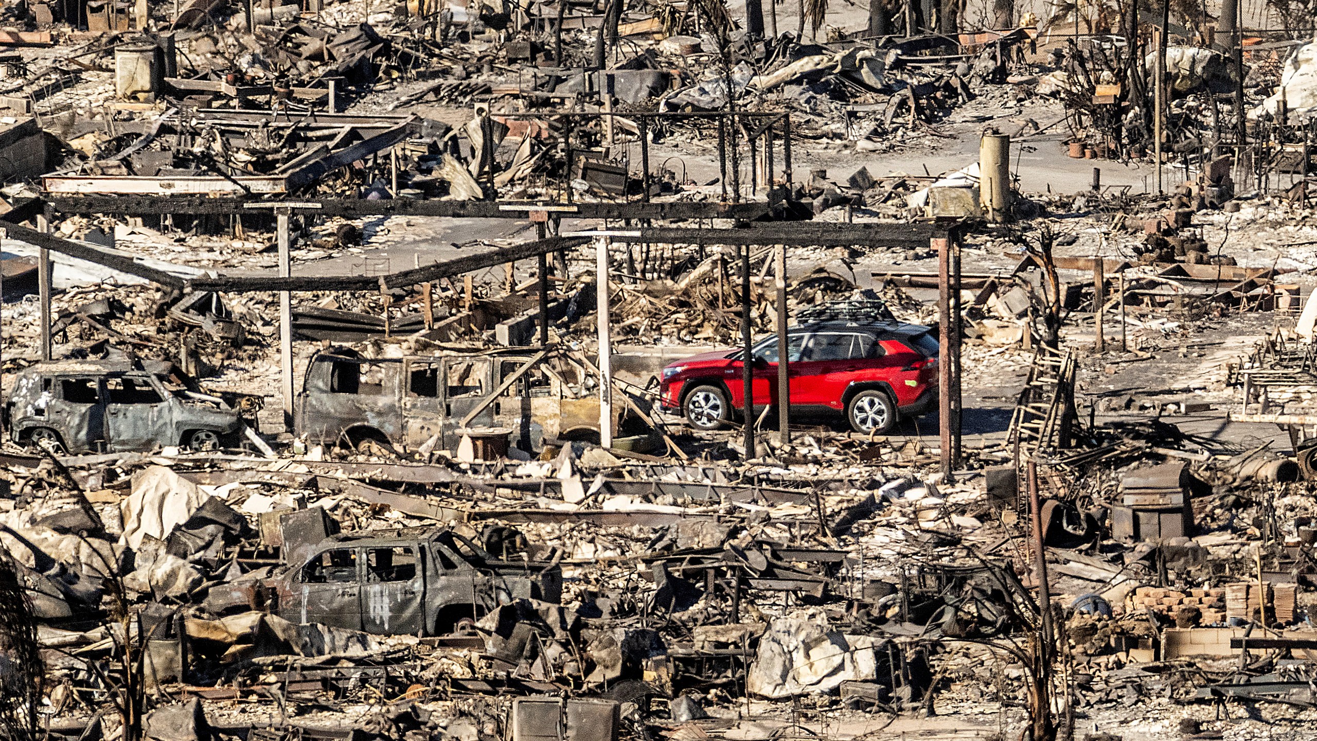 A car drives past homes and vehicles destroyed by the Palisades Fire at the Pacific Palisades Bowl Mobile Estates on Sunday, Jan. 12, 2025, in Los Angeles. (AP Photo/Noah Berger)