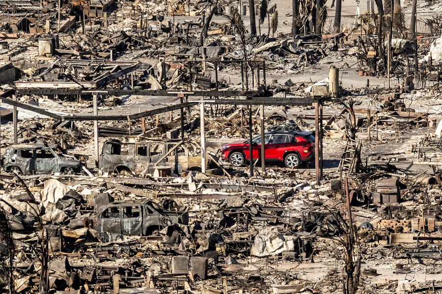 A car drives past homes and vehicles destroyed by the Palisades Fire at the Pacific Palisades Bowl Mobile Estates on Sunday, Jan. 12, 2025, in Los Angeles. (AP Photo/Noah Berger)