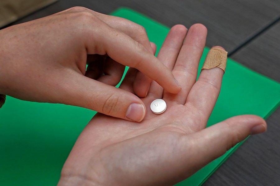 FILE - A patient prepares to take the first of two combination pills, mifepristone, for a medication abortion during a visit to a clinic in Kansas City, Kan., on, Oct. 12, 2022. (AP Photo/Charlie Riedel, File)