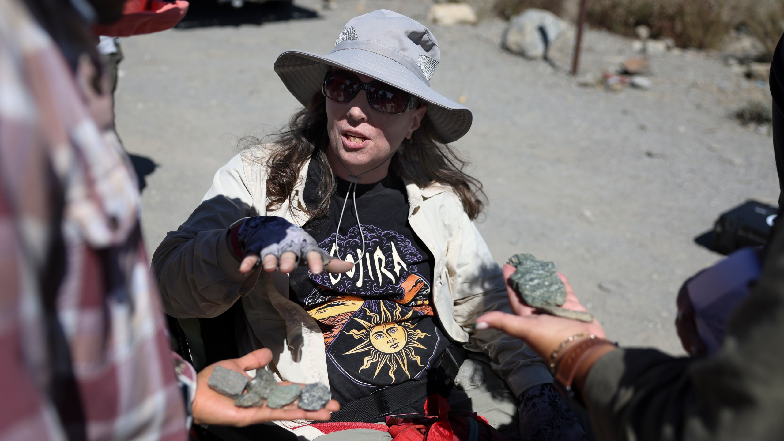 Jennifer Piatek, a planetary geologist at Central Connecticut State University, speaks with attendees on stones found during an accessible field trip to the San Andreas Fault organized by the International Association of Geoscience Diversity Thursday, Sept. 26, 2024, in San Bernadino, Calif. (AP Photo/Ryan Sun)