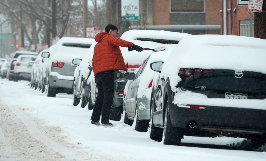 A motorist clears snow off his vehicle parked along First Avenue as a winter storm sweeps over the intermountain West, plunging temperatures into the single digits and bringing along a light snow in its wake Saturday, Jan. 18, 2025, in Denver. (AP Photo/David Zalubowski)