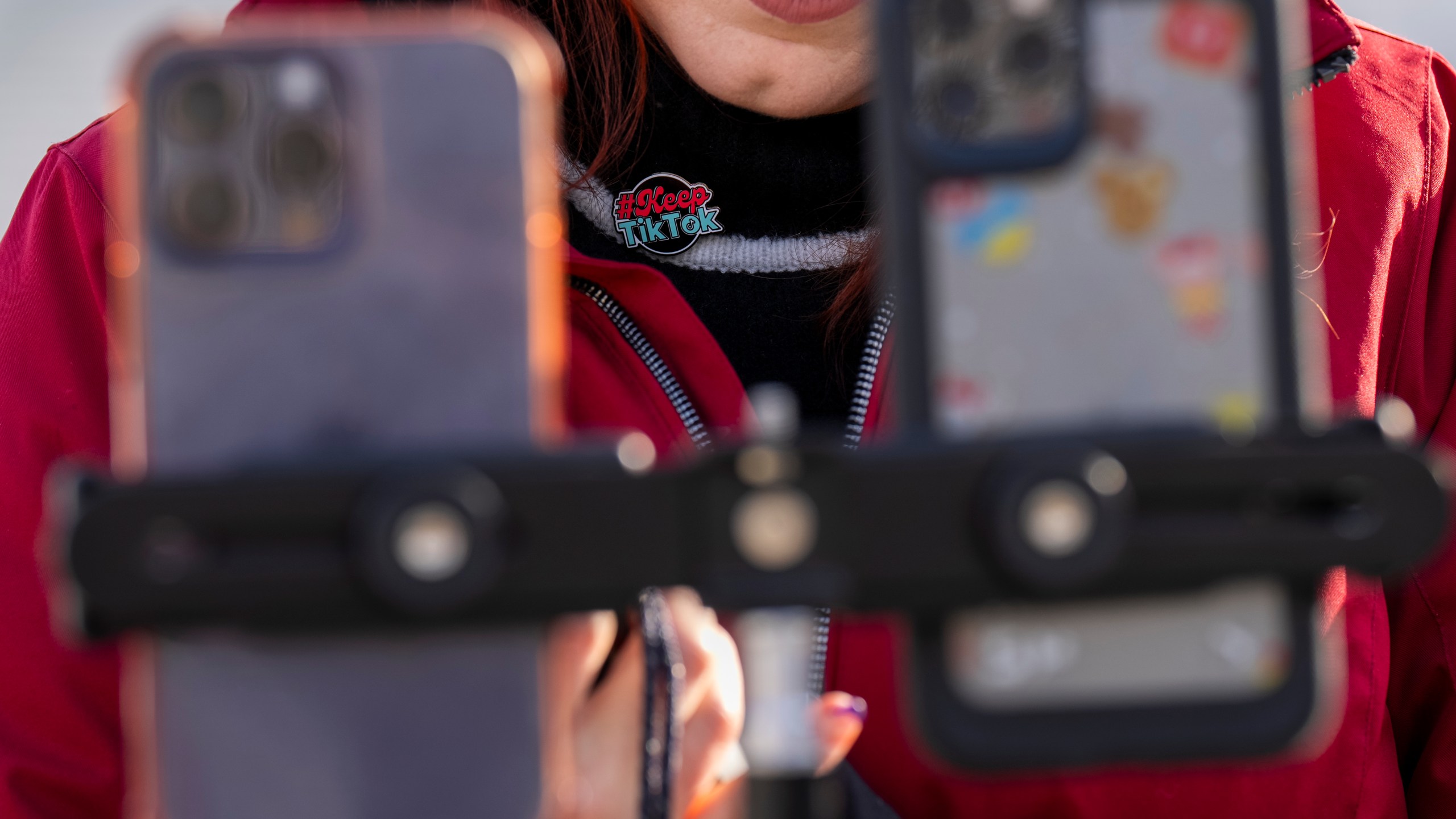 Wearing a button in support of TikTok, Tiffany Cianci, who says she is a "long-form educational content creator," livestreams to TikTok outside the Supreme Court, Friday, Jan. 10, 2025, in Washington. (AP Photo/Jacquelyn Martin)