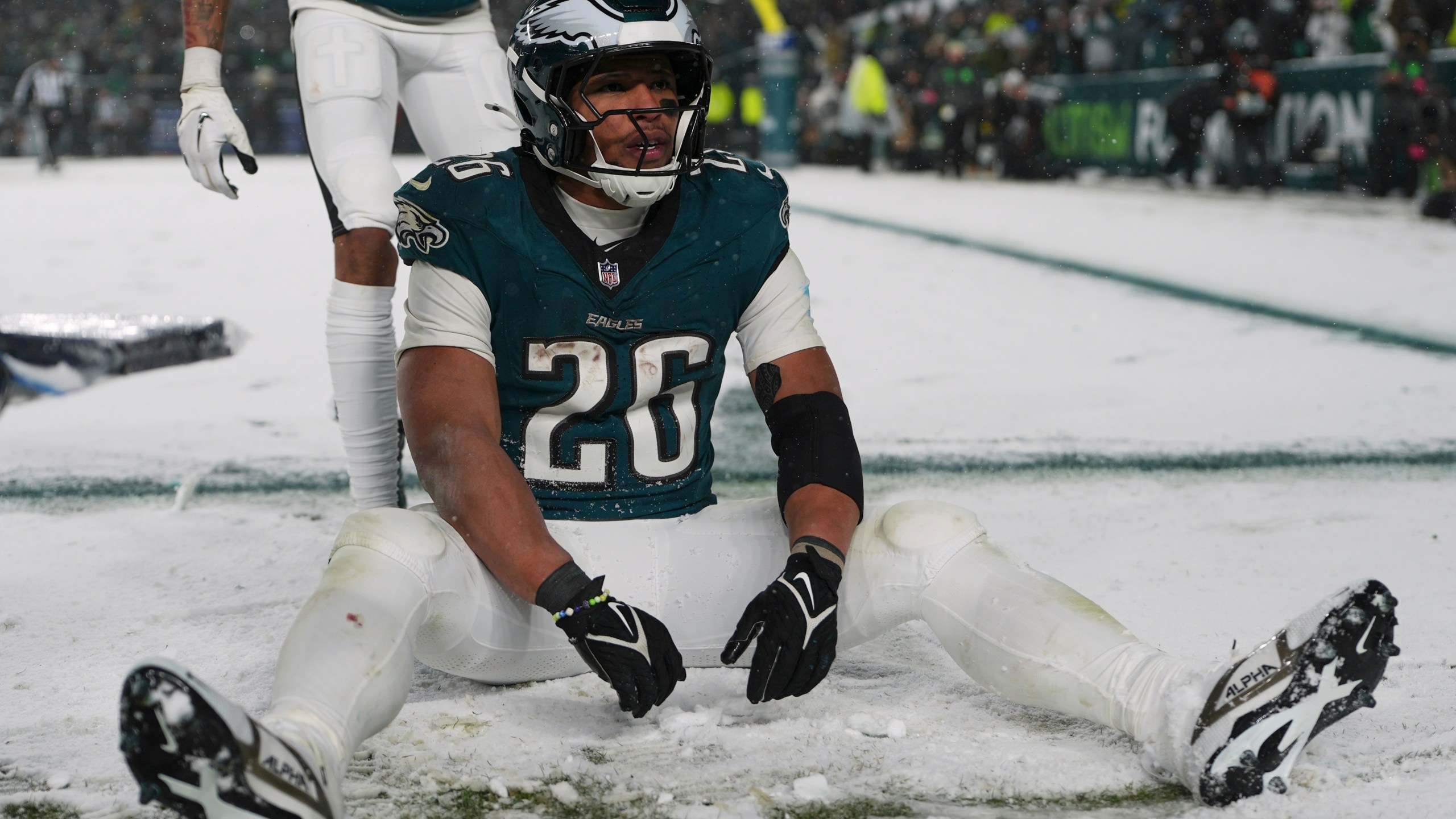 Philadelphia Eagles running back Saquon Barkley (26) sits in the snow as he celebrates his touchdown during the second half of an NFL football NFC divisional playoff game against the Los Angeles Rams on Sunday, Jan. 19, 2025, in Philadelphia. (AP Photo/Matt Slocum)