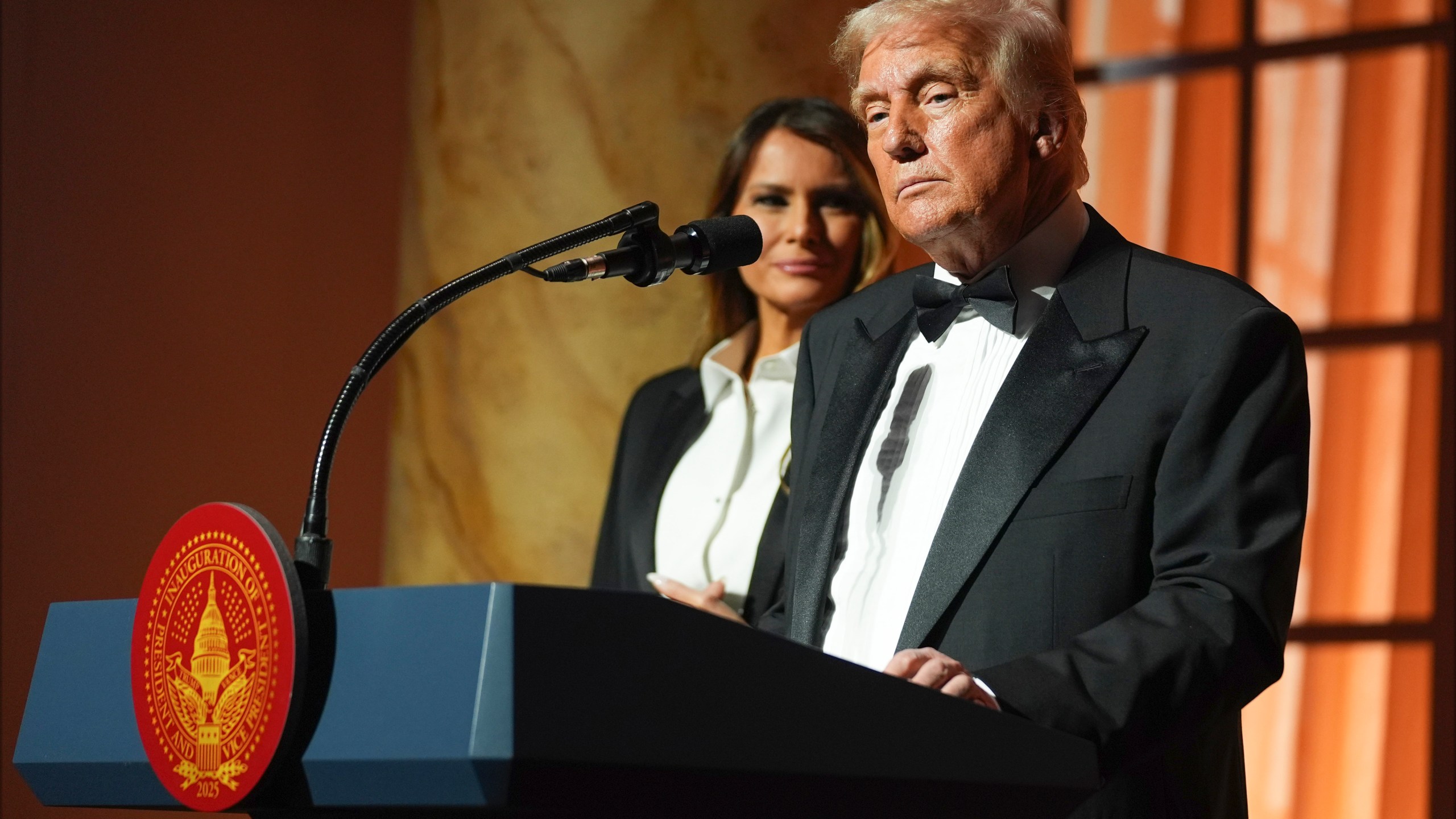 President-elect Donald Trump speaks at a dinner at the Building Museum, Sunday, Jan. 19, 2025, in Washington, as Melania Trump listens. (AP Photo/Evan Vucci)