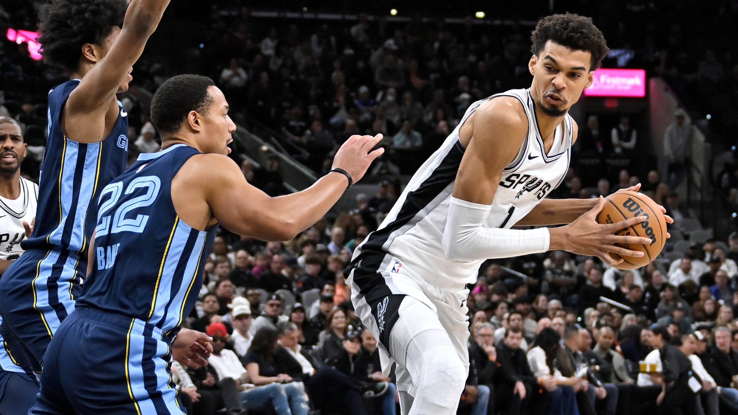 San Antonio Spurs' Victor Wembanyama (1) drives against Memphis Grizzlies' Desmond Bane (22) and Jaylen Wells during the first half of an NBA basketball game, Friday, Jan. 17, 2025, in San Antonio. (AP Photo/Darren Abate)