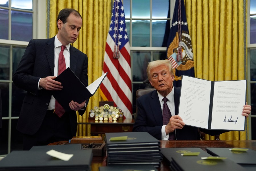 President Donald Trump holds up an executive order commuting sentences for people convicted of Jan. 6 offenses in the Oval Office of the White House, Monday, Jan. 20, 2025, in Washington. (AP Photo/Evan Vucci)