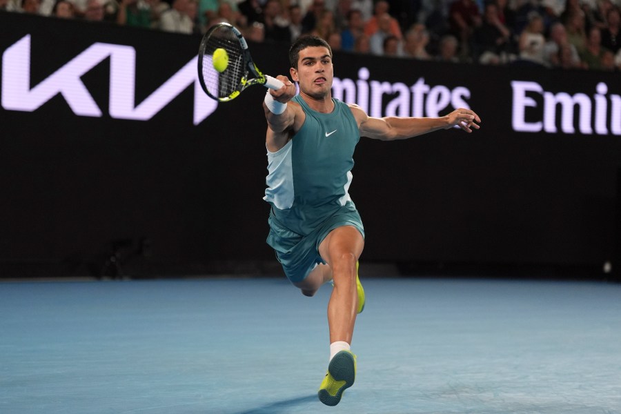 Carlos Alcaraz of Spain plays a forehand return to Novak Djokovic of Serbia during their quarterfinal match at the Australian Open tennis championship in Melbourne, Australia, Tuesday, Jan. 21, 2025. (AP Photo/Ng Han Guan)