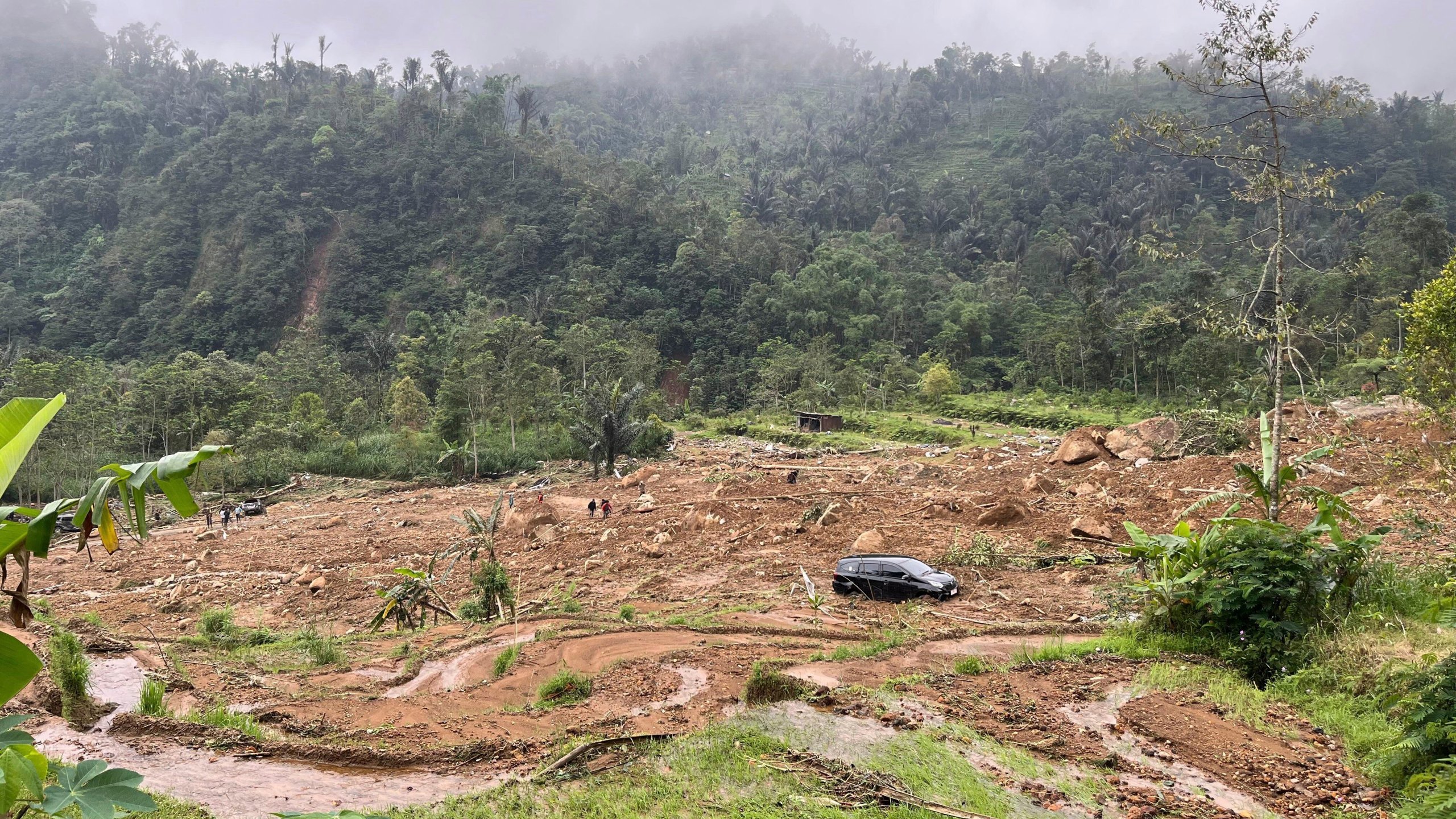 The wreckage of a car is stuck in the mud at an area affected by a landslide following a flash flood in Pekalongan, Central Java, Indonesia, Wednesday, Jan. 22, 2025. (AP Photo/Janaki DM)