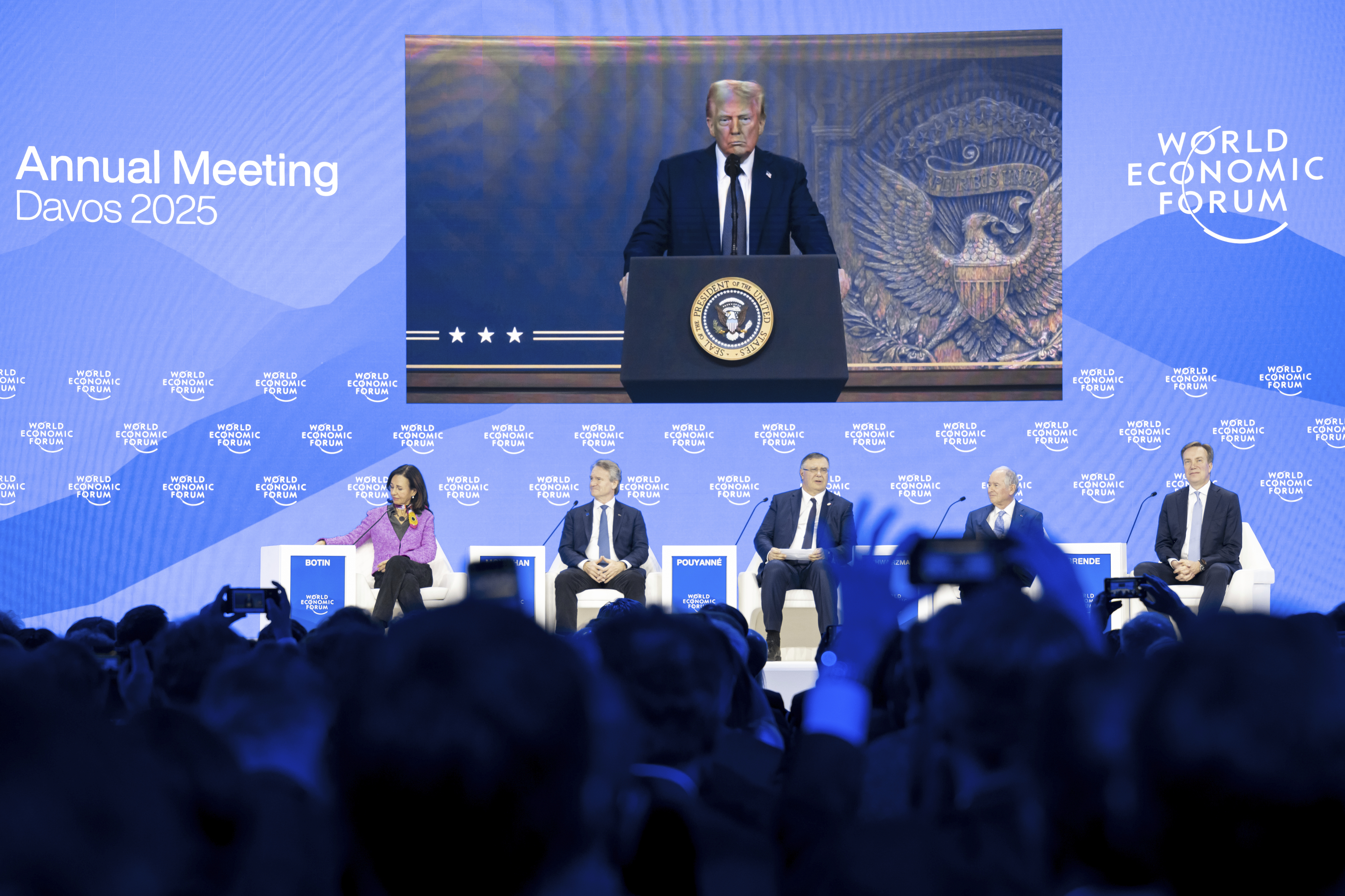 US President Donald J. Trump is shown on screens as he addresses via remote connection a plenary session in the Congress Hall, during the 55th annual meeting of the World Economic Forum (WEF), in Davos, Switzerland, Thursday, Jan. 23, 2025. (Michael Buholzer/Keystone via AP)