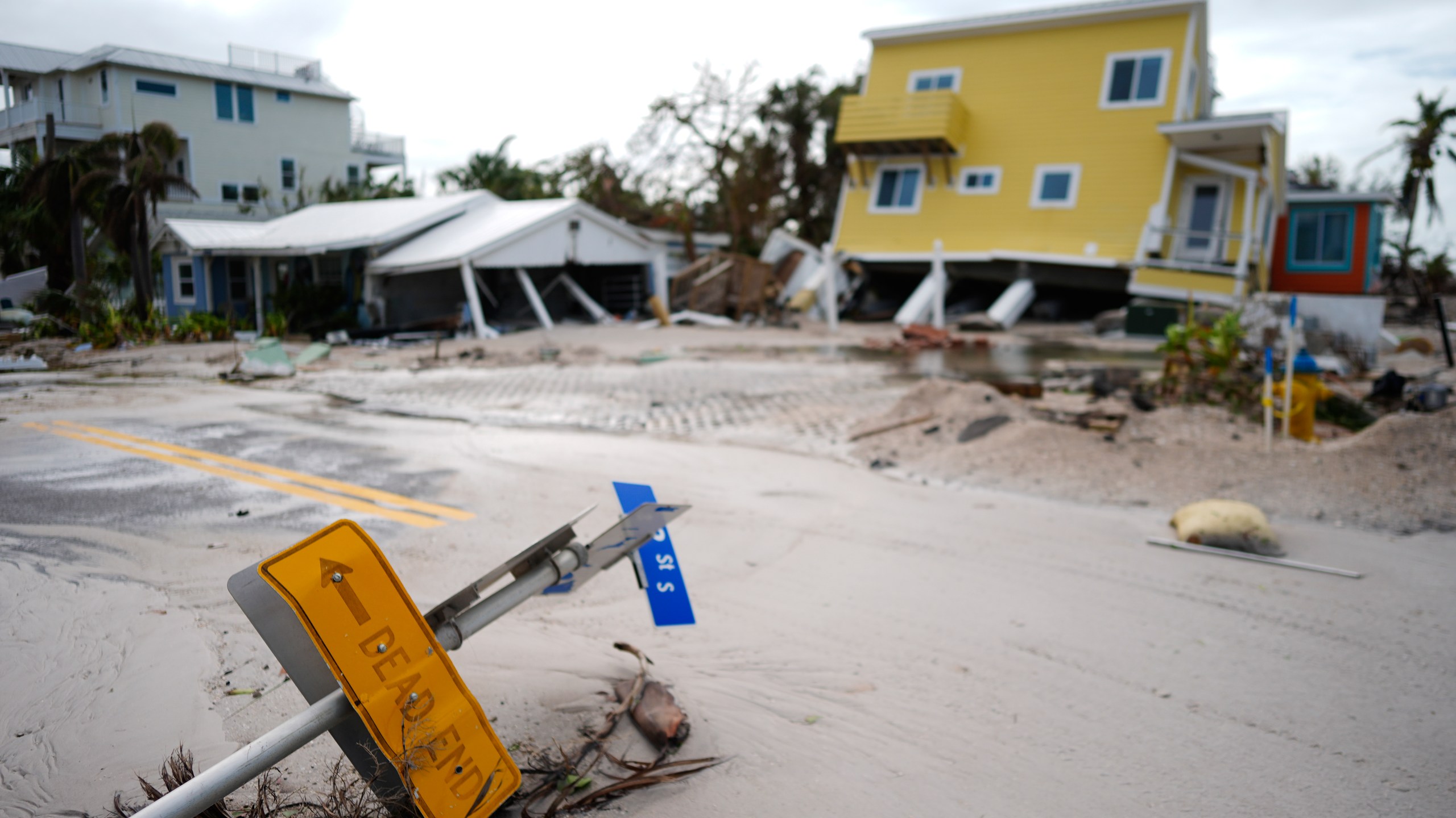 FILE - A house sits toppled off its stilts after the passage of Hurricane Milton, alongside an empty lot where a home was swept away by Hurricane Helene, in Bradenton Beach on Anna Maria Island, Florida, Oct. 10, 2024. (AP Photo/Rebecca Blackwell, File)