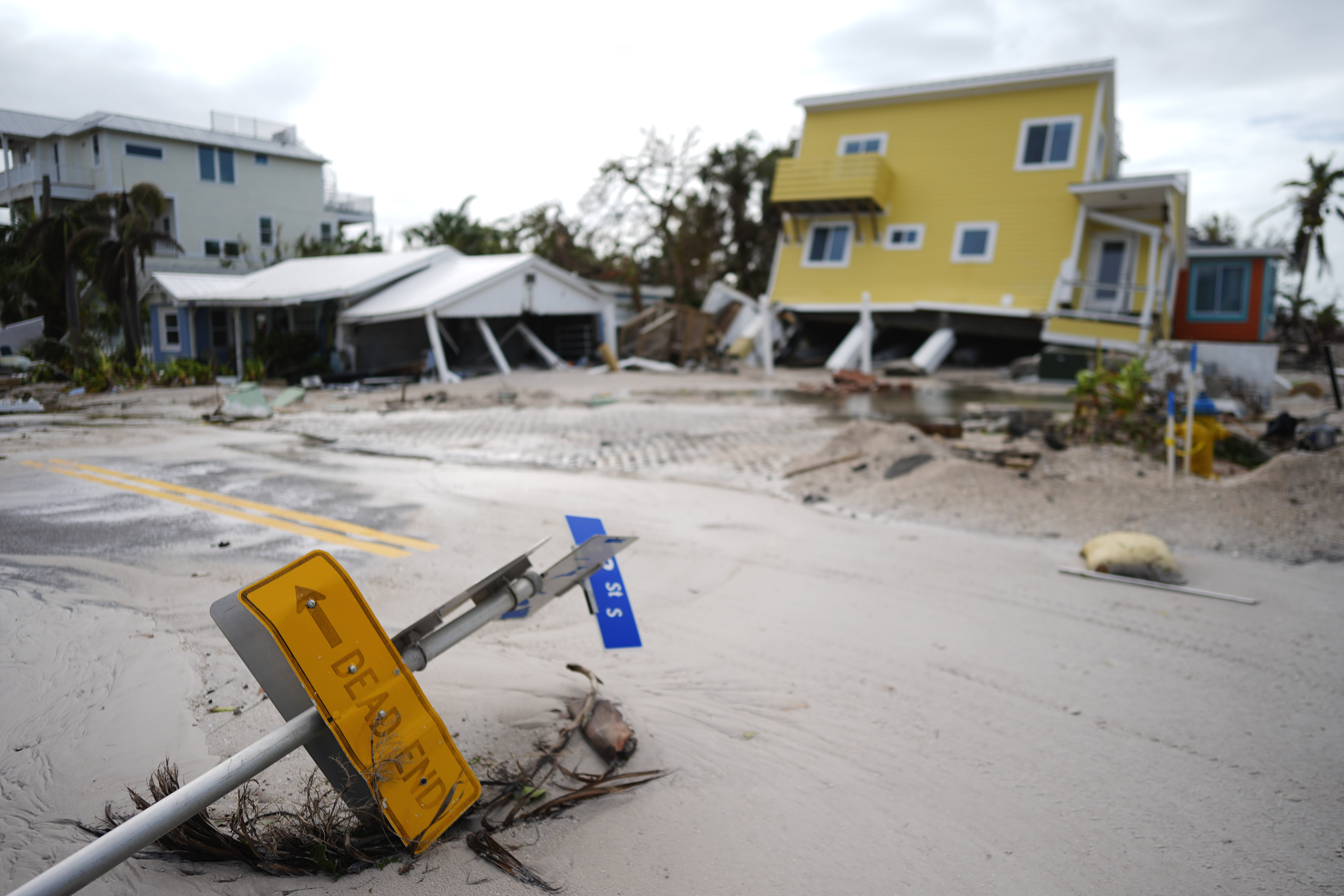 FILE - A house sits toppled off its stilts after the passage of Hurricane Milton, alongside an empty lot where a home was swept away by Hurricane Helene, in Bradenton Beach on Anna Maria Island, Florida, Oct. 10, 2024. (AP Photo/Rebecca Blackwell, File)