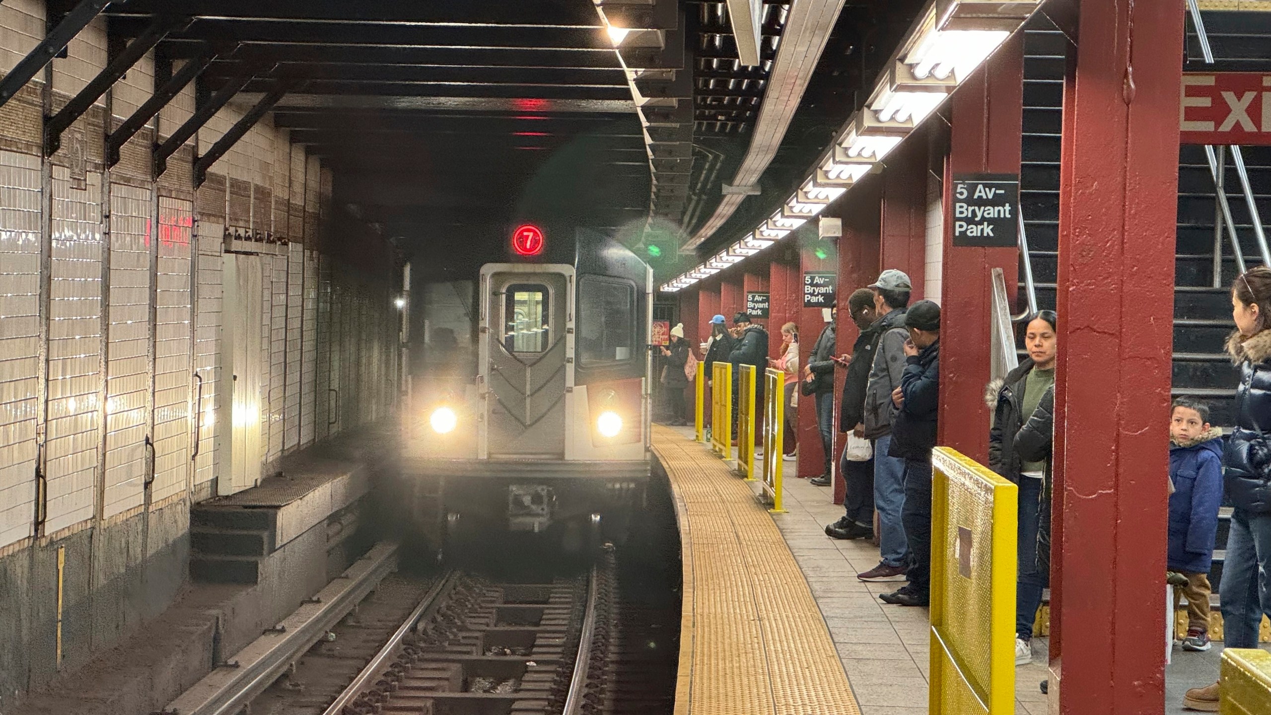 FILE - Subway riders stand near yellow barriers on a platform of the 7 train in New York on Tuesday, March 26, 2024. (AP Photo/Cedar Attanasio, File)