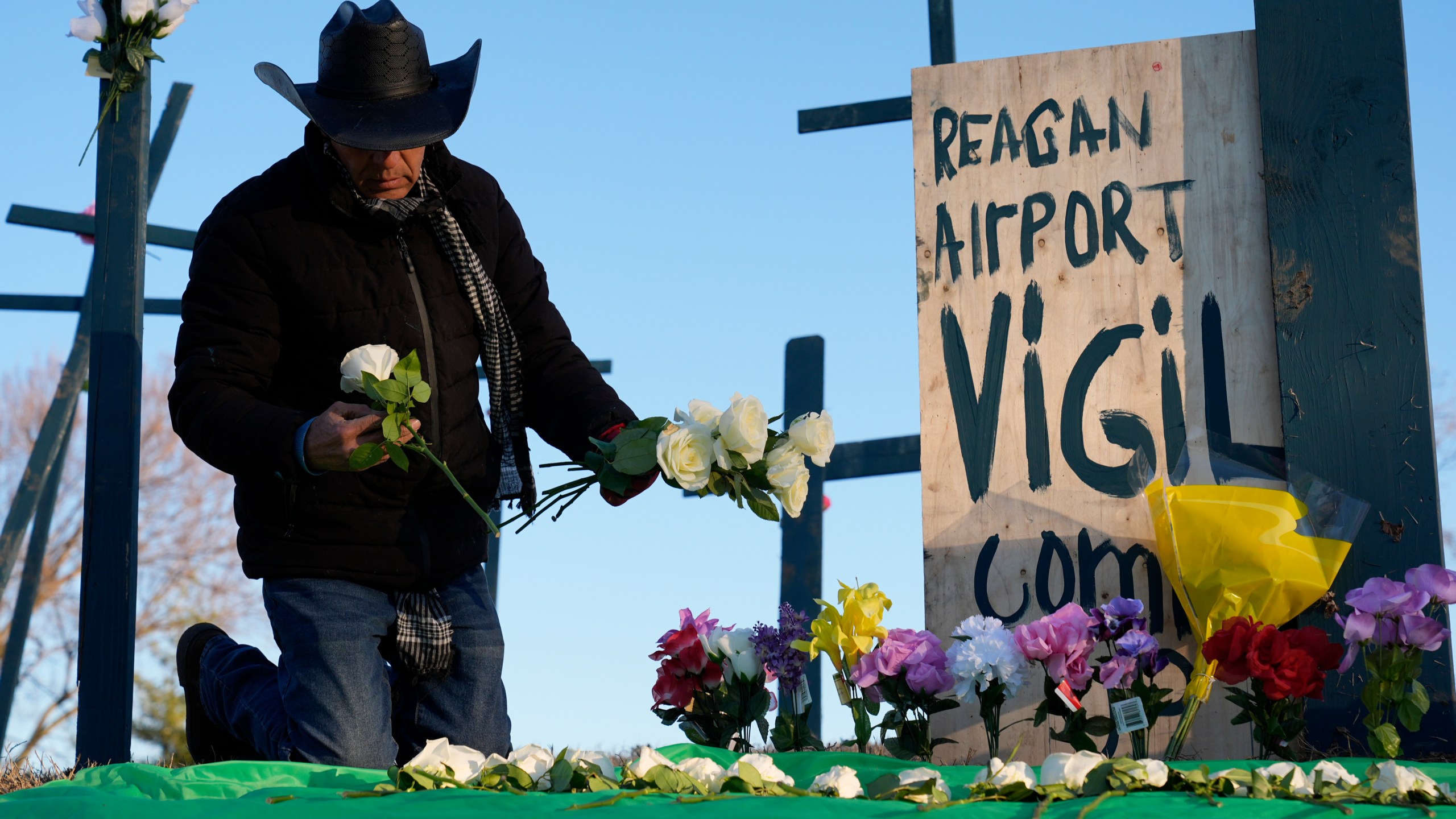 Roberto Marquez, of Dallas, places flowers at a memorial for the 67 victims of a midair collision between an Army helicopter and an American Airlines flight from Kansas near the Ronald Reagan Washington National Airport, Saturday, Feb. 1, 2025, in Arlington, Va. (AP Photo/Carolyn Kaster)