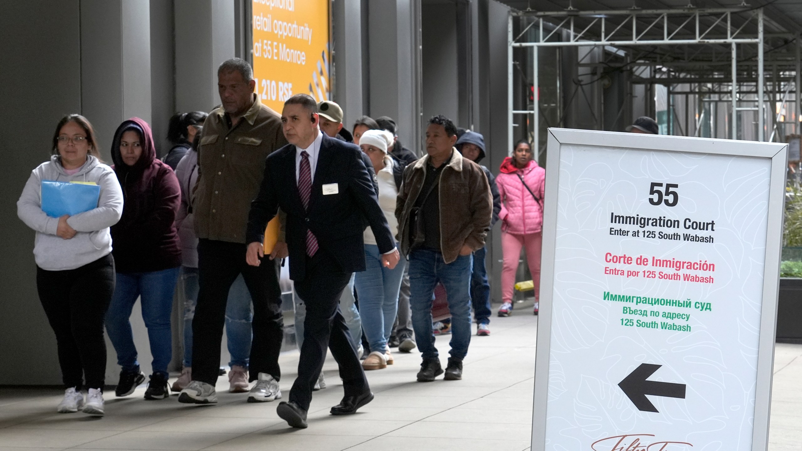 FILE - After waiting in a cue, people are led into a downtown Chicago building where an immigration court presides Tuesday, Nov. 12, 2024, in Chicago. (AP Photo/Charles Rex Arbogast, File)