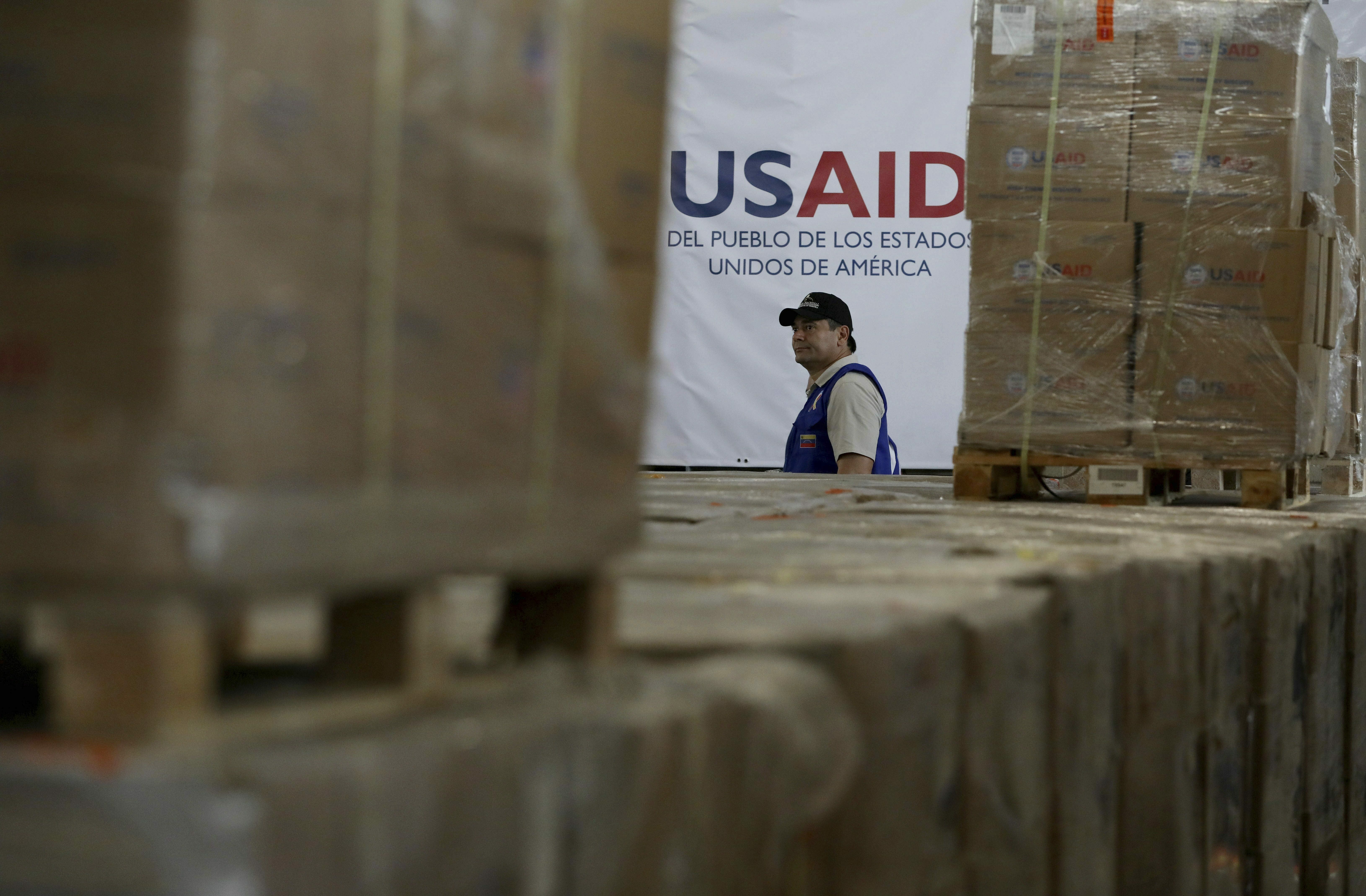 FILE - A man walks past boxes of USAID humanitarian aid at a warehouse at the Tienditas International Bridge on the outskirts of Cucuta, Colombia, Feb. 21, 2019, on the border with Venezuela. (AP Photo/Fernando Vergara)