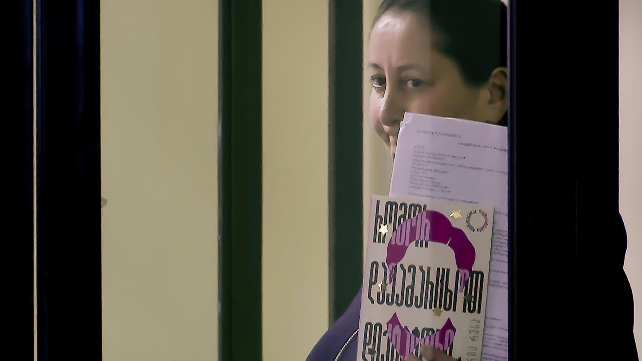 In this image made from a Formula TV video, Mzia Amabhlobeli, a Georgian journalist and founder of the independent media outlets Batumelebi and Netgazeti, stands in a defendants’ cage in a court in Batumi, Georgia, on Saturday, Feb. 1, 2025, and holds a book by Nobel Peace Prize laureate and journalist Maria Ressa titled, "How to Stand Up to a Dictator." (Formula TV via AP)