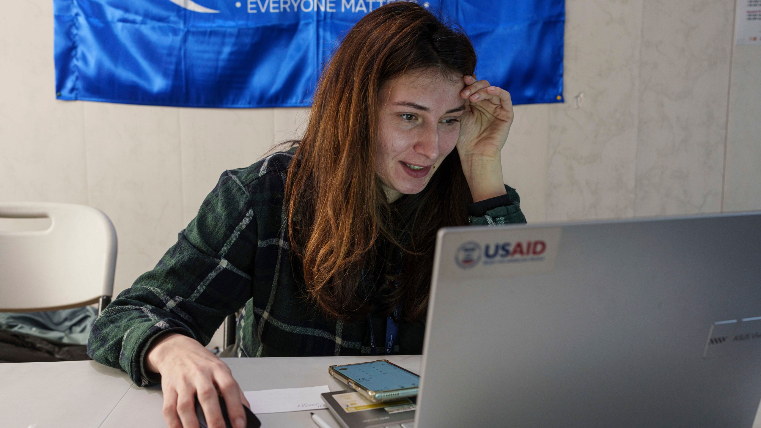 A social worker looks at a laptop with a USAID logo, at a center for displaced people in Pavlohrad, Ukraine, Saturday, Feb. 1, 2024. (AP Photo/Evgeniy Maloletka)