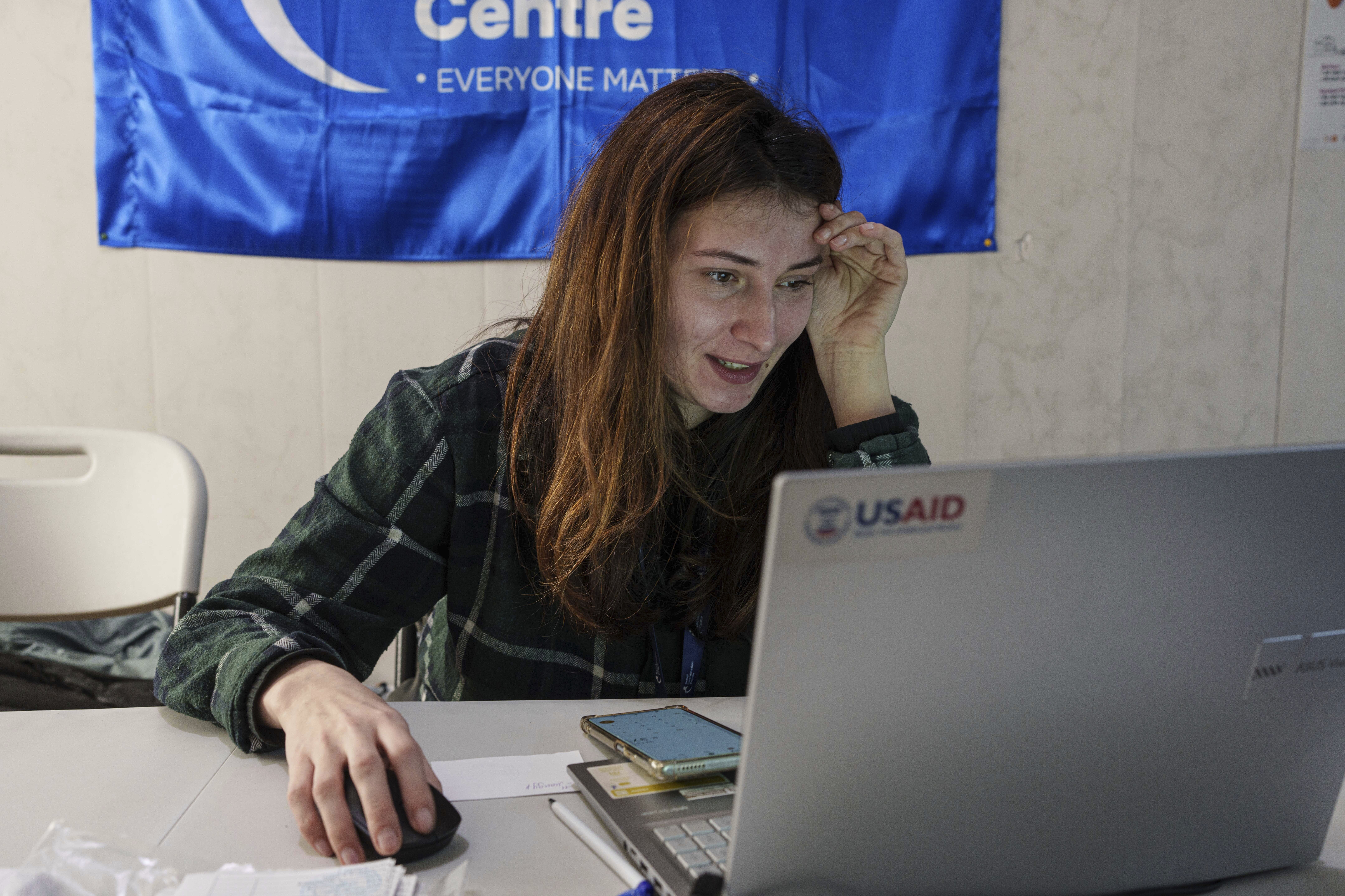 A social worker looks at a laptop with a USAID logo, at a center for displaced people in Pavlohrad, Ukraine, Saturday, Feb. 1, 2024. (AP Photo/Evgeniy Maloletka)