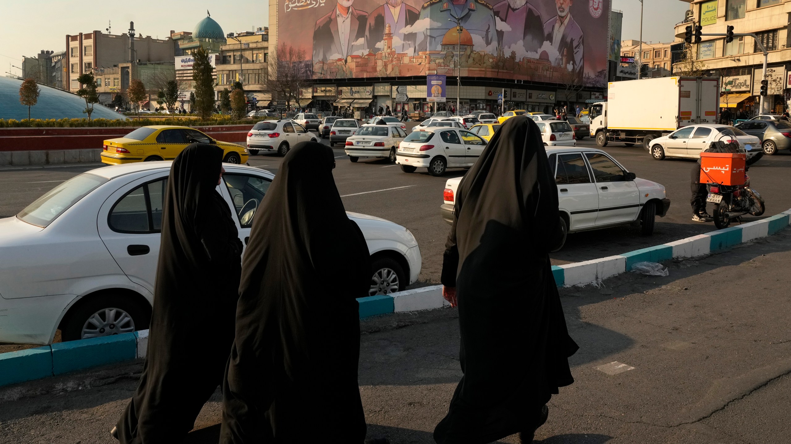 People walk on Enqelab-e-Eslami (Islamic Revolution) square near a huge banner showing the late commander of the Iran's Revolutionary Guard expeditionary Quds Force, Gen. Qassem Soleimani, center, who was killed in a U.S. drone attack in 2020, and Hezbollah and Hamas officials killed by Israel, in Tehran, Iran, Tuesday, Jan. 21, 2025. (AP Photo/Vahid Salemi)