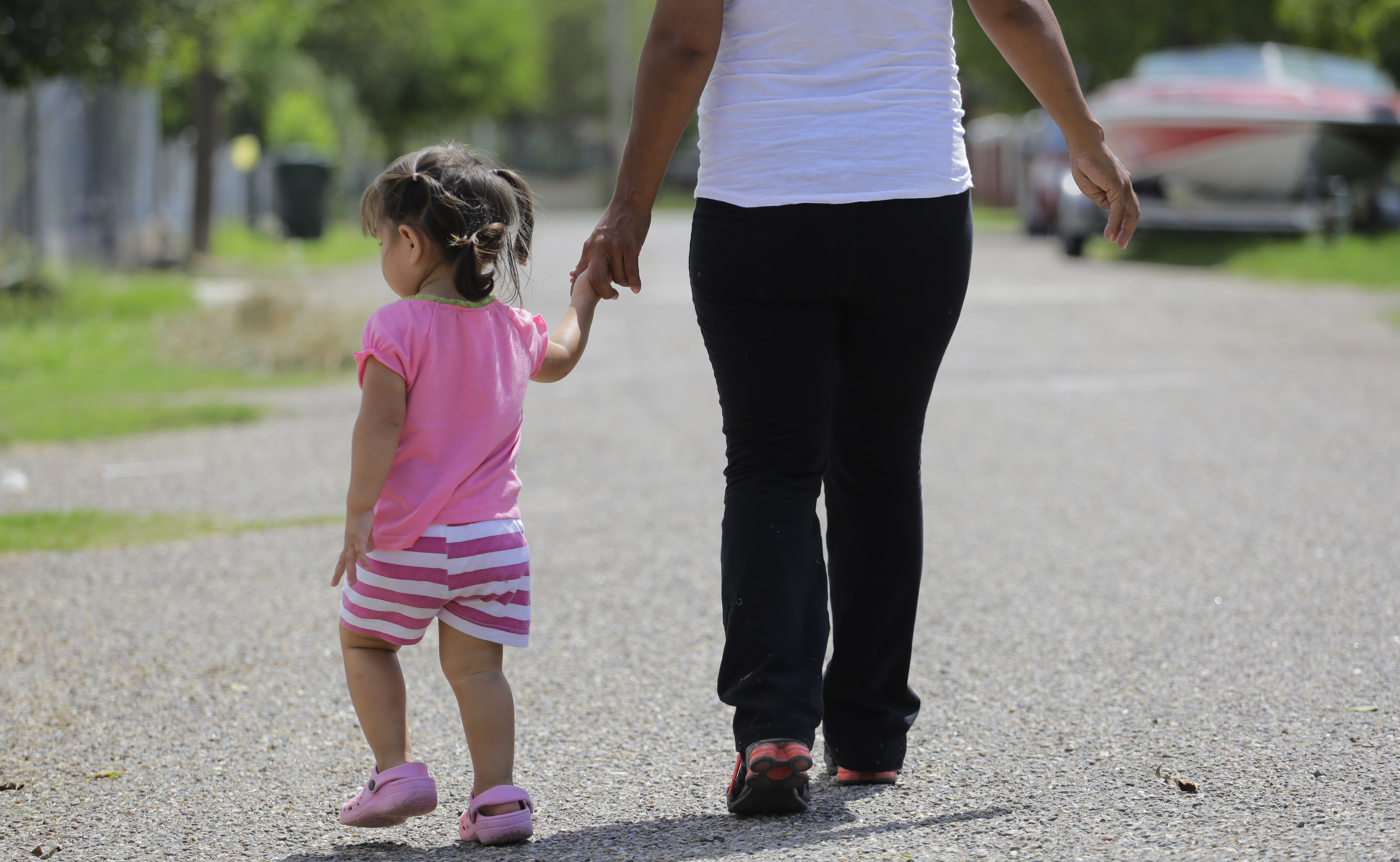 FILE - In this Sept. 16, 2015, photo, a woman in Sullivan City, Texas, who said she entered the country illegally, walks with her daughter who was born in the United States, but was denied a birth certificate. (AP Photo/Eric Gay, File)